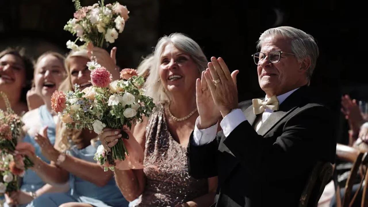 Parents and a bridesmaid clapping in gold and dusty blue at Gold Mountain