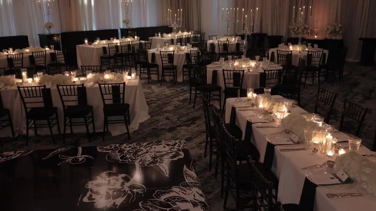 Candlelit reception ballroom with black chairs, white florals, and long banquet tables at Red Berry Estate