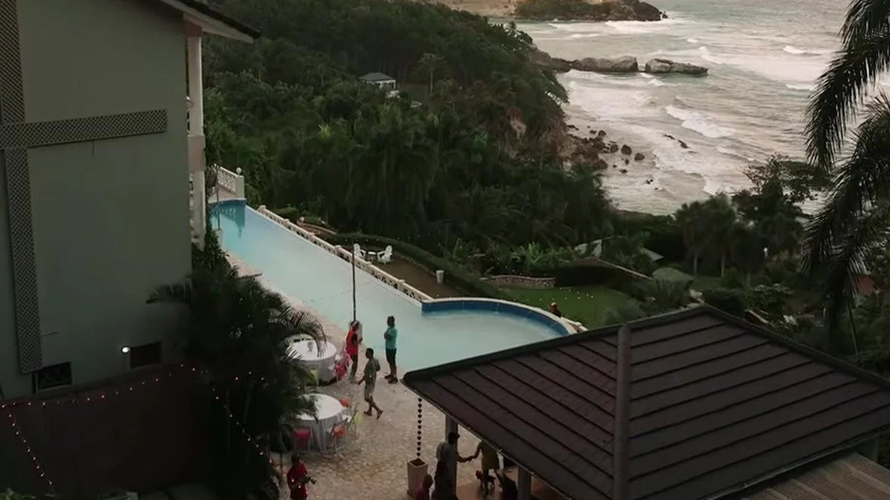 Infinity pool and white tables on a cliff patio above a rocky Dominican beach