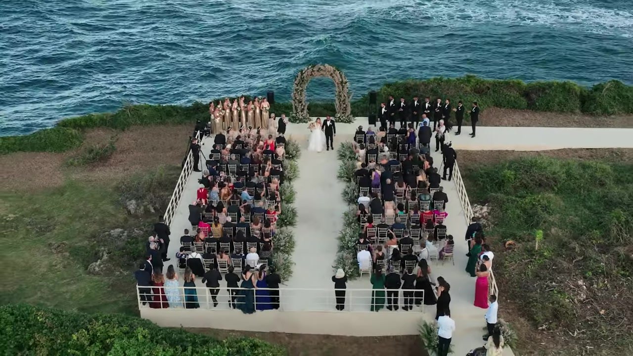 Aerial of Felix and Victoria walking the cliff aisle to a circular floral arch