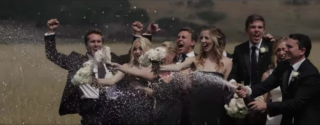 Wedding party cheering and spraying champagne in a golden Crested Butte meadow