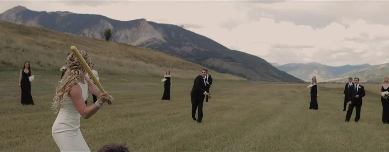 Lauren at bat and Davey pitching in a mountain meadow, wedding party fielding in black