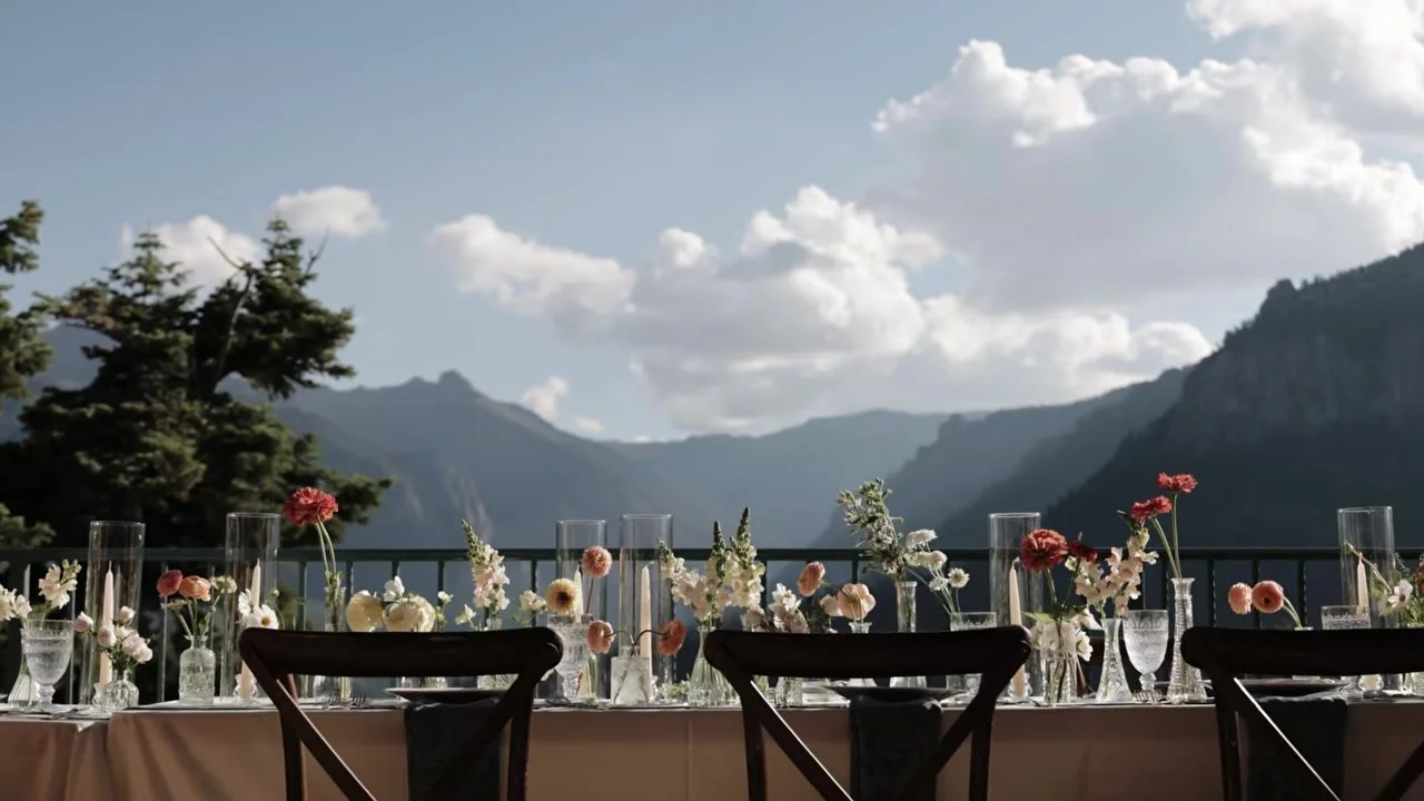Long reception table with peach florals and taper candles above the valley at Gold Mountain
