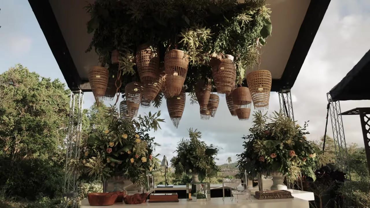 Outdoor bar with hanging wicker lanterns, a greenery canopy, and peach florals on a private Dominican farm