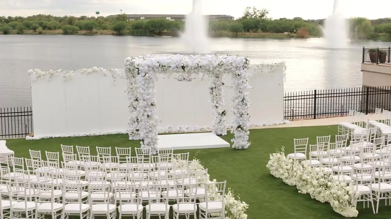 Empty lakeside ceremony with a white floral arch, Chiavari chairs, and fountain lake at Red Berry Estate