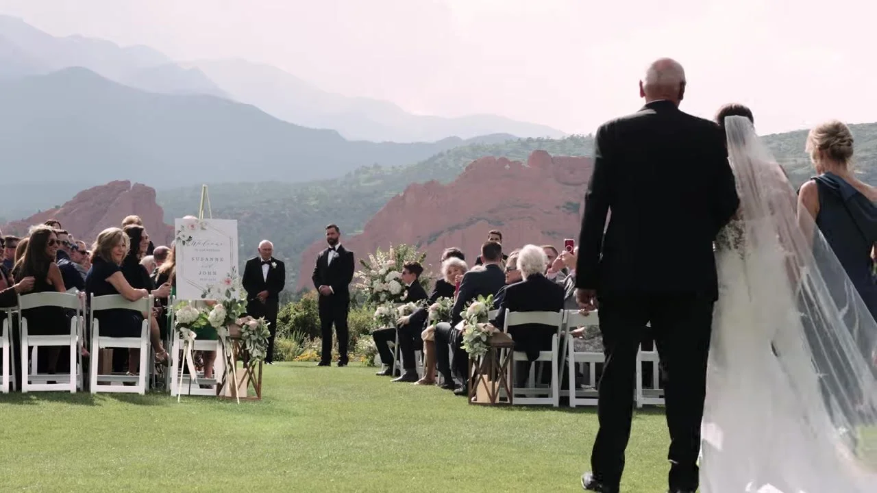 Processional down the aisle toward the red rocks with her father at Garden of the Gods