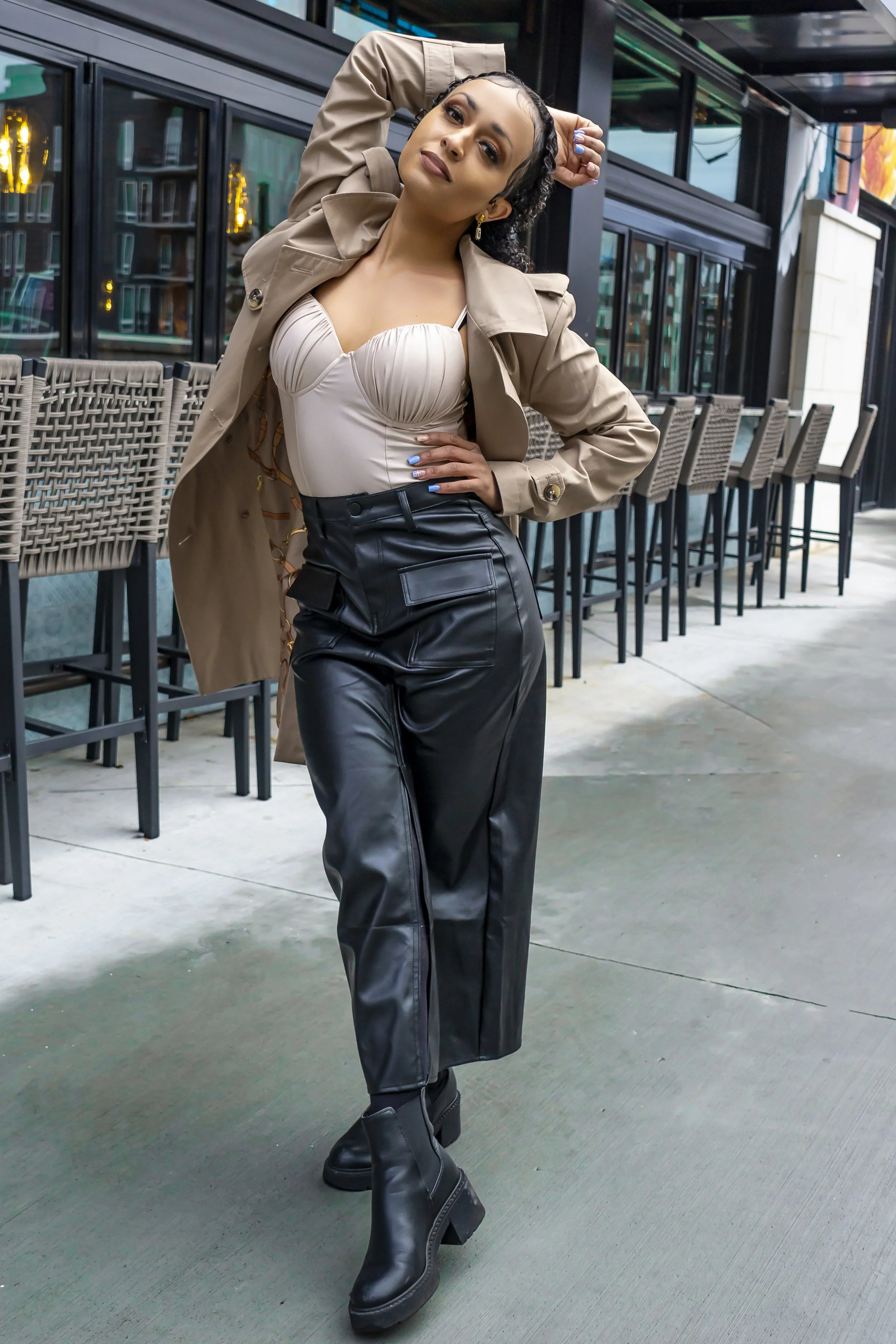 Fashionable woman in trench coat and leather pants posing outdoors