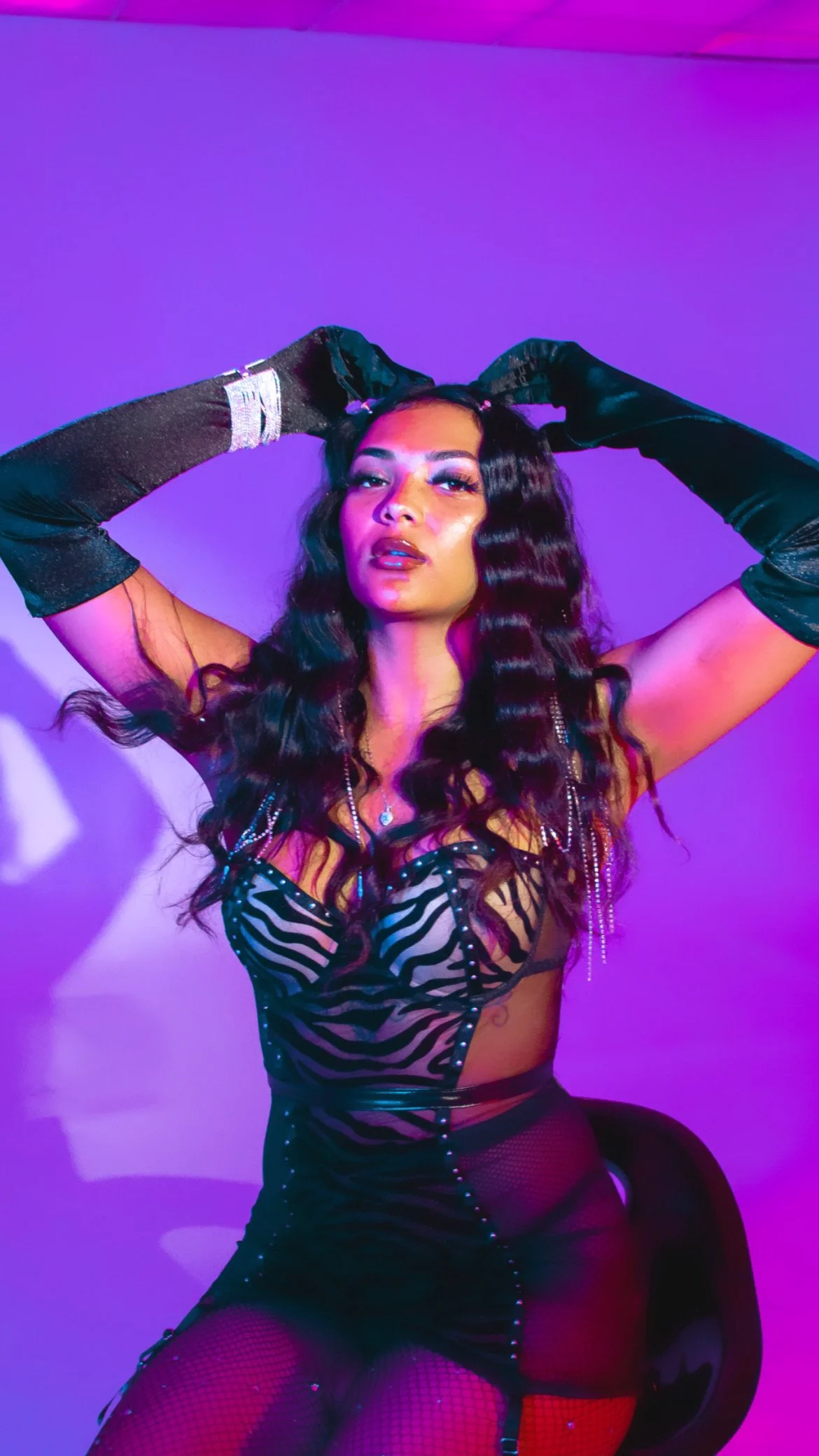 Woman in zebra-patterned outfit with black gloves and purple lighting.