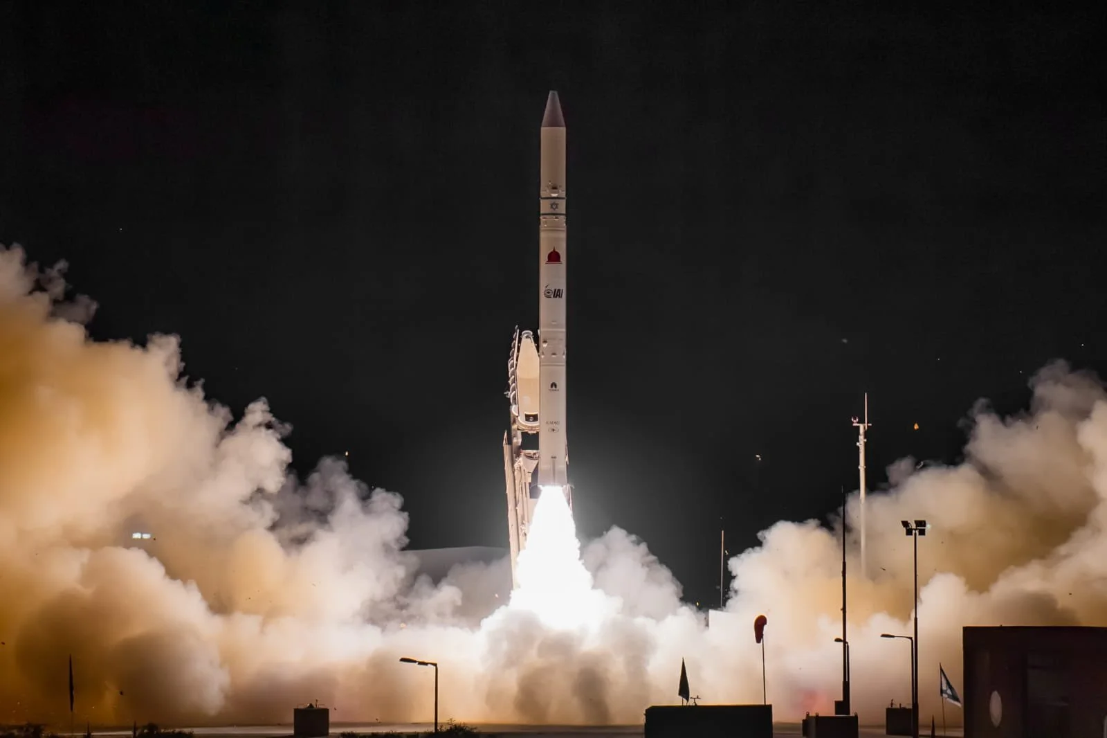 A rocket launch at night with bright flames and clouds of smoke rising from the ground.