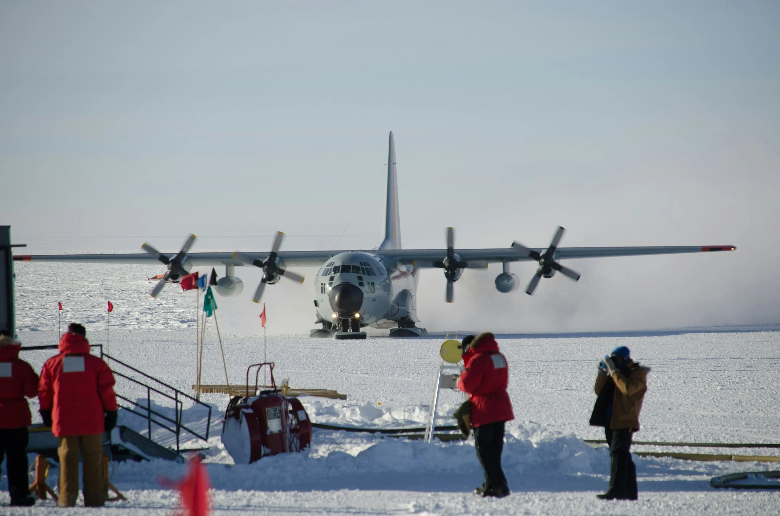 Aircraft landing on snowy runway with people observing