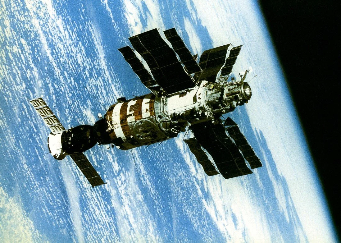 The space station docked in orbit above Earth, with Earth’s blue and white cloud-covered surface visible below.