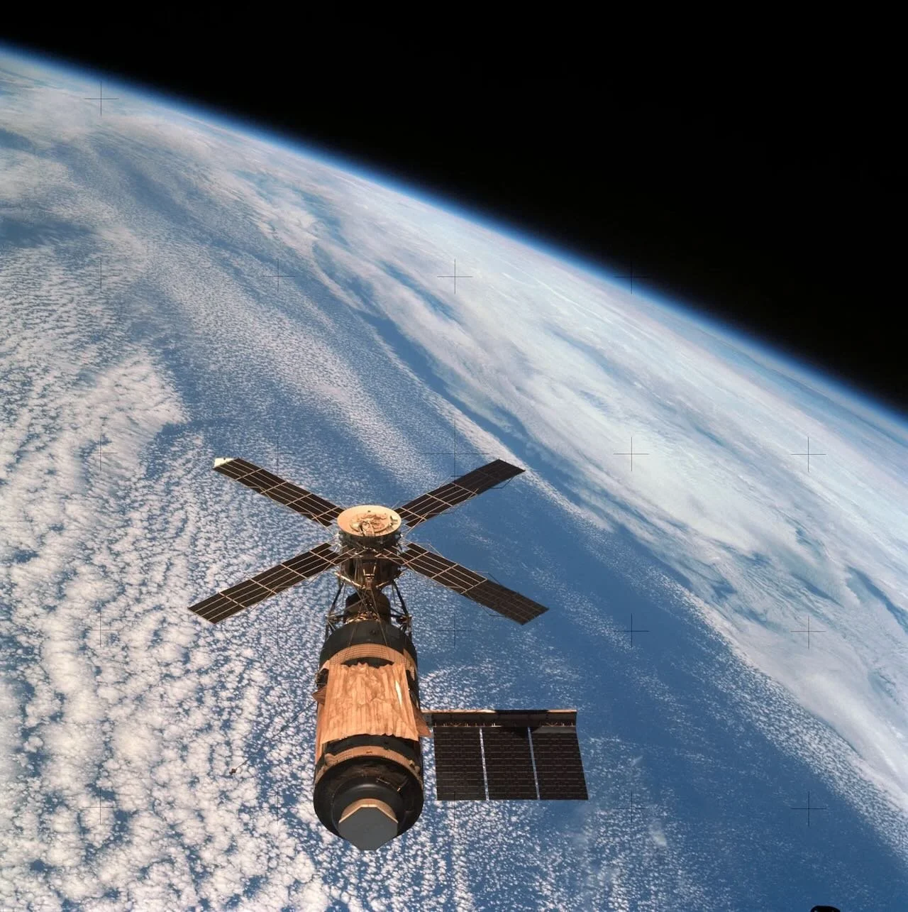 A satellite with solar panels orbiting Earth in space, with the planet's clouds and atmosphere visible below.