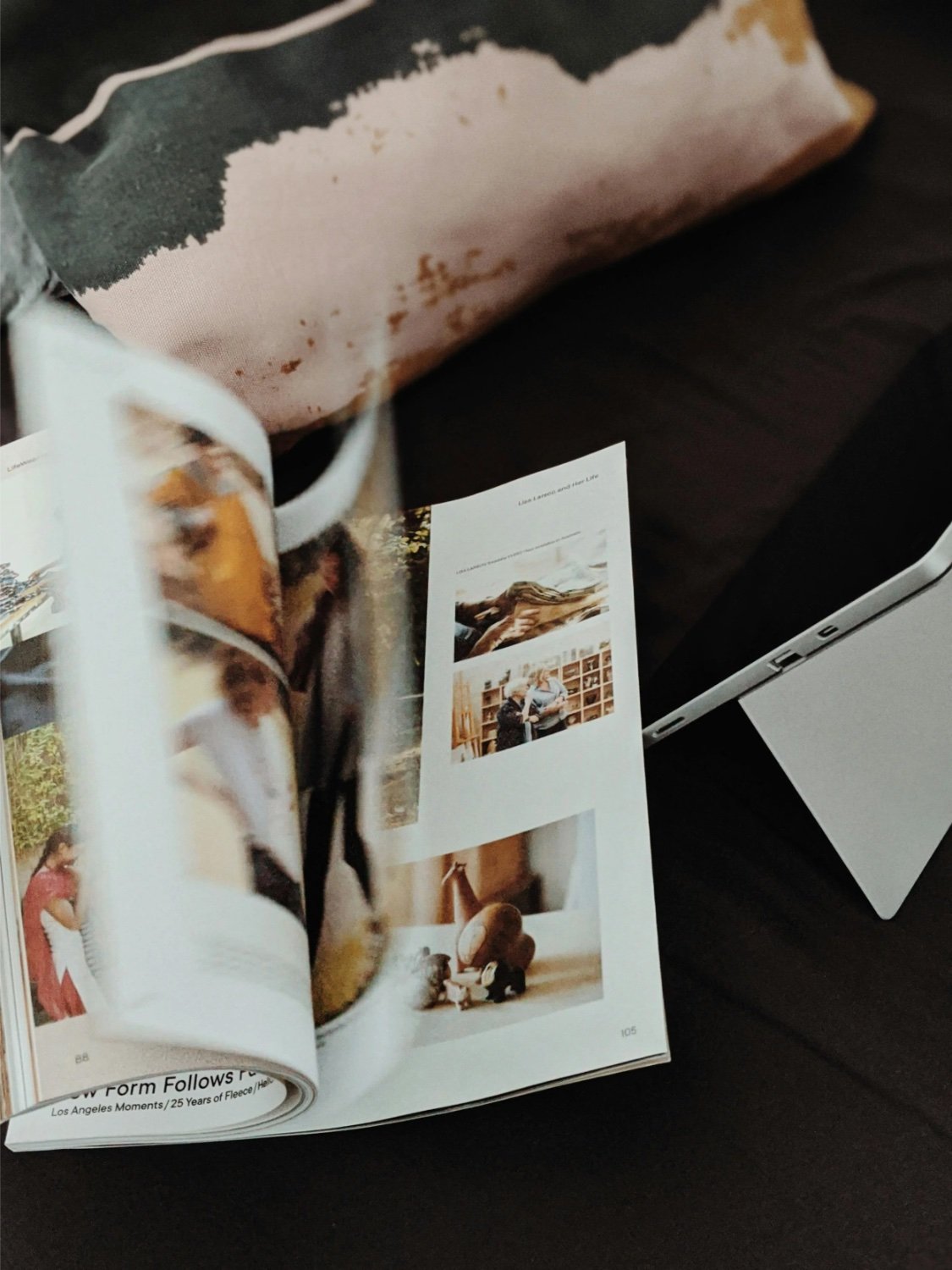 Open magazine featuring photos of people and objects, resting on a dark surface.