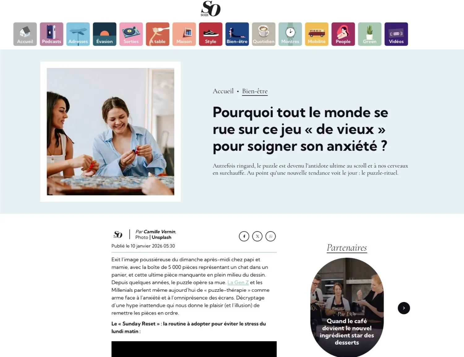 Three women sitting at a table playing a puzzle game, two of them are focused on the puzzle while one girl smiles and holds a puzzle piece.