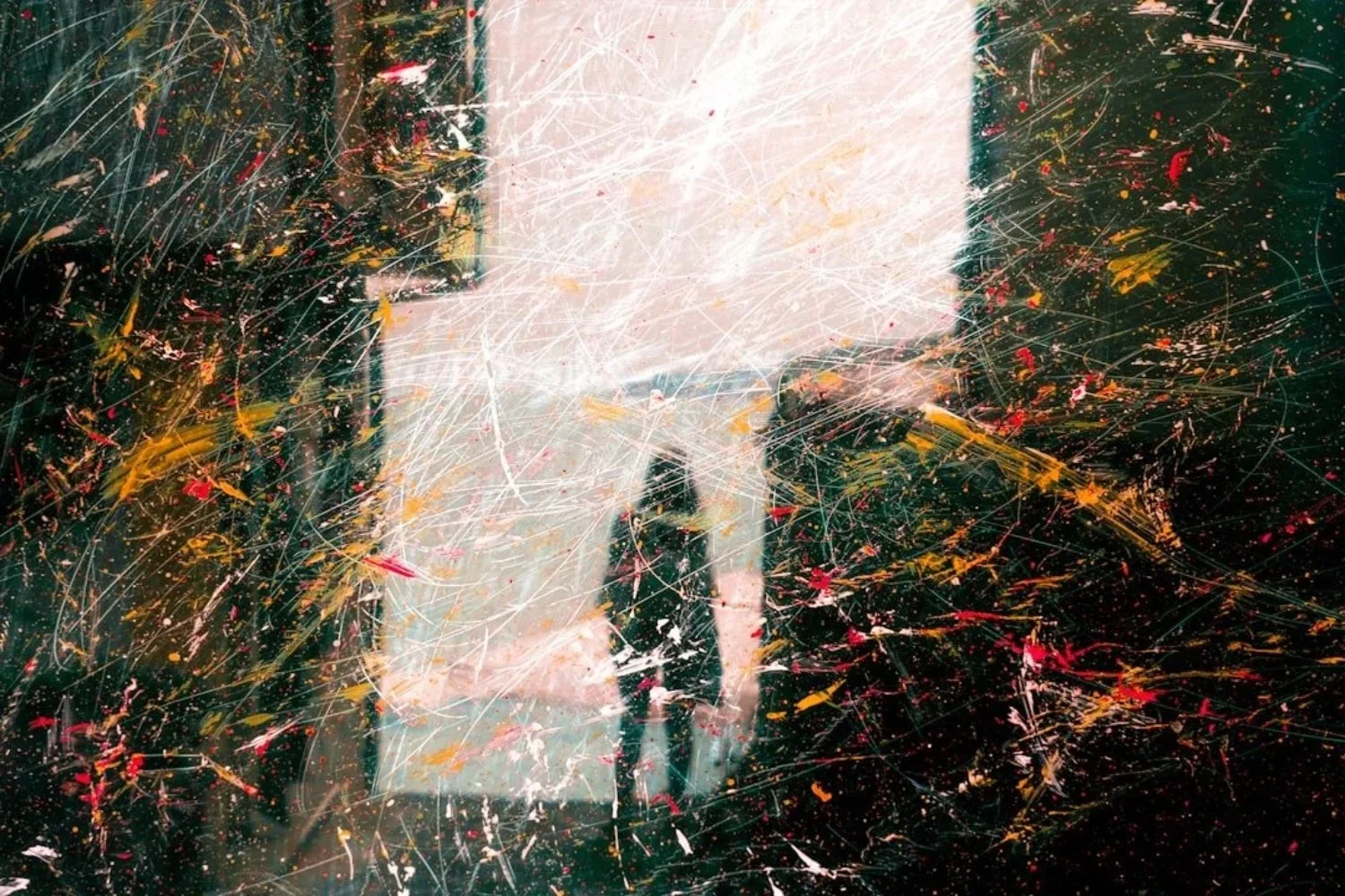 A person taking a photo of a colorful abstract painting with a smartphone, with the painting having splattered paint and vibrant colors.