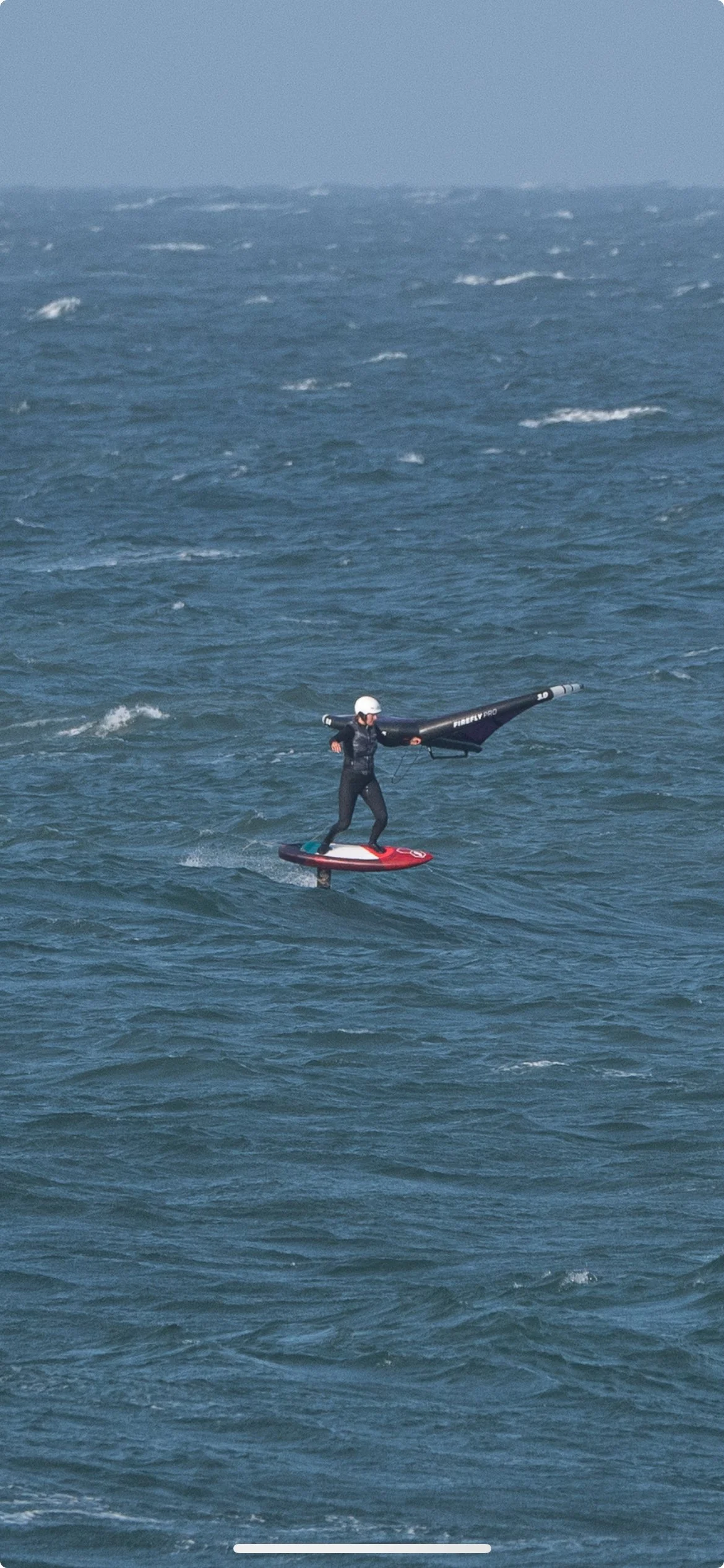 Person auf einem E-Board mit einem Wasserski-Propeller, der auf dem Wasser fährt, bei windigem Wetter.