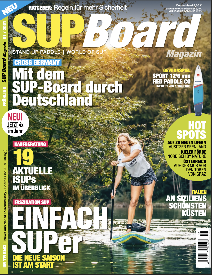 Frauen beim Stand-Up-Paddling auf einem Fluss in einer bewaldeten Umgebung an einem sonnigen Tag.