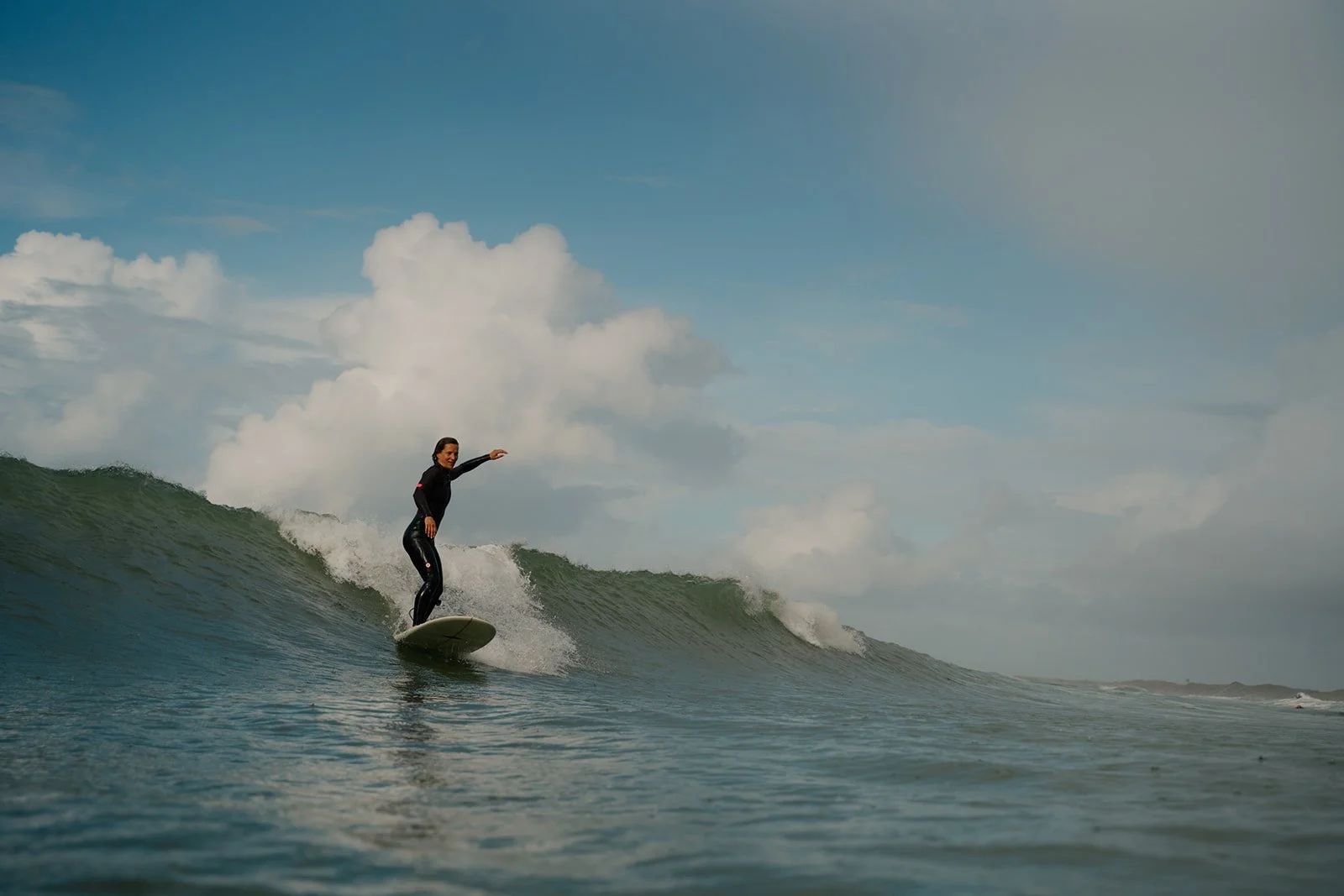 Frau beim Surfen auf einer Welle im Meer bei bewölktem Himmel