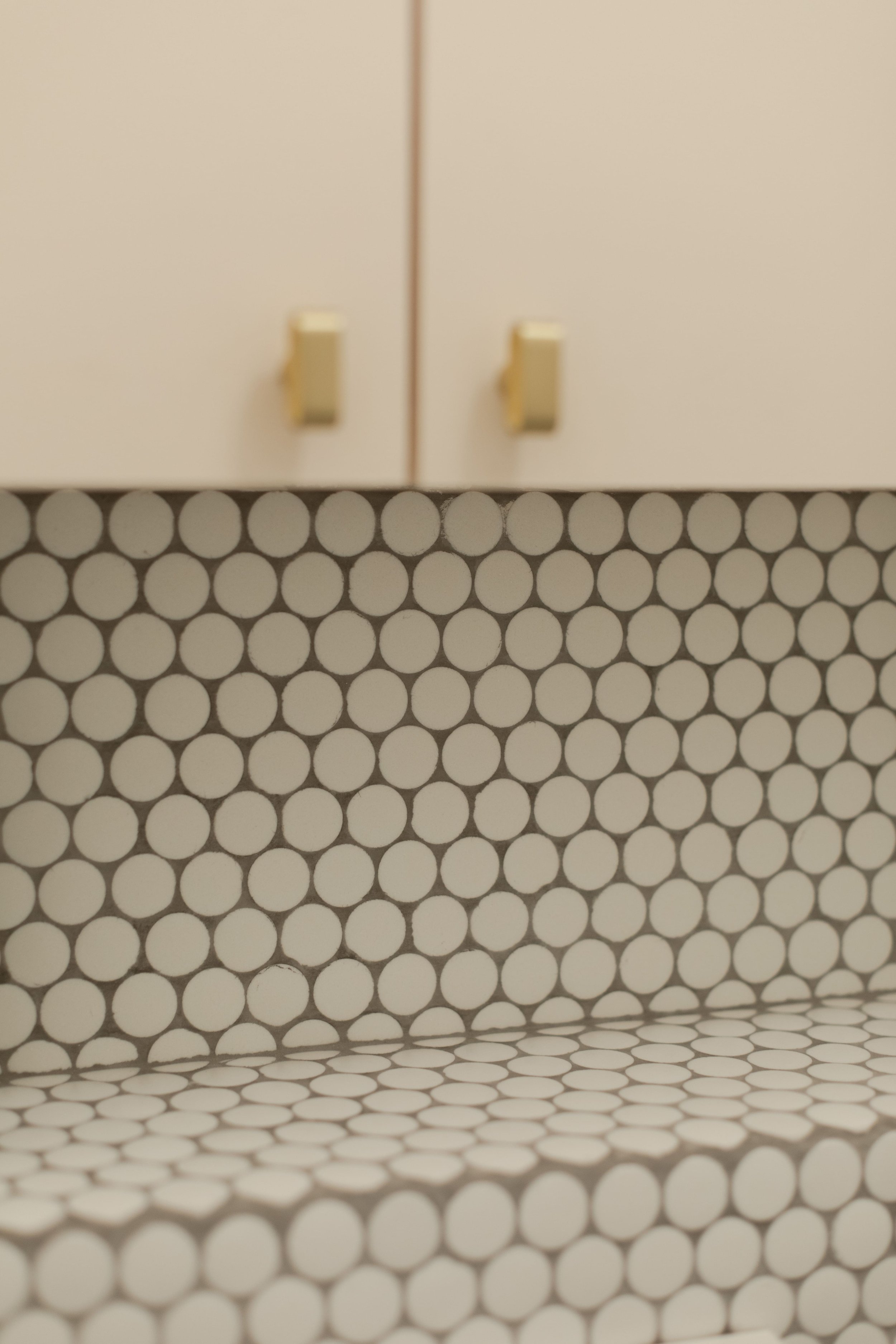 Vue éloignée d'une armoire en haut, avec poignées jaunes, et un banc en dessous avec un rembourrage de motif rond blanc et noir.