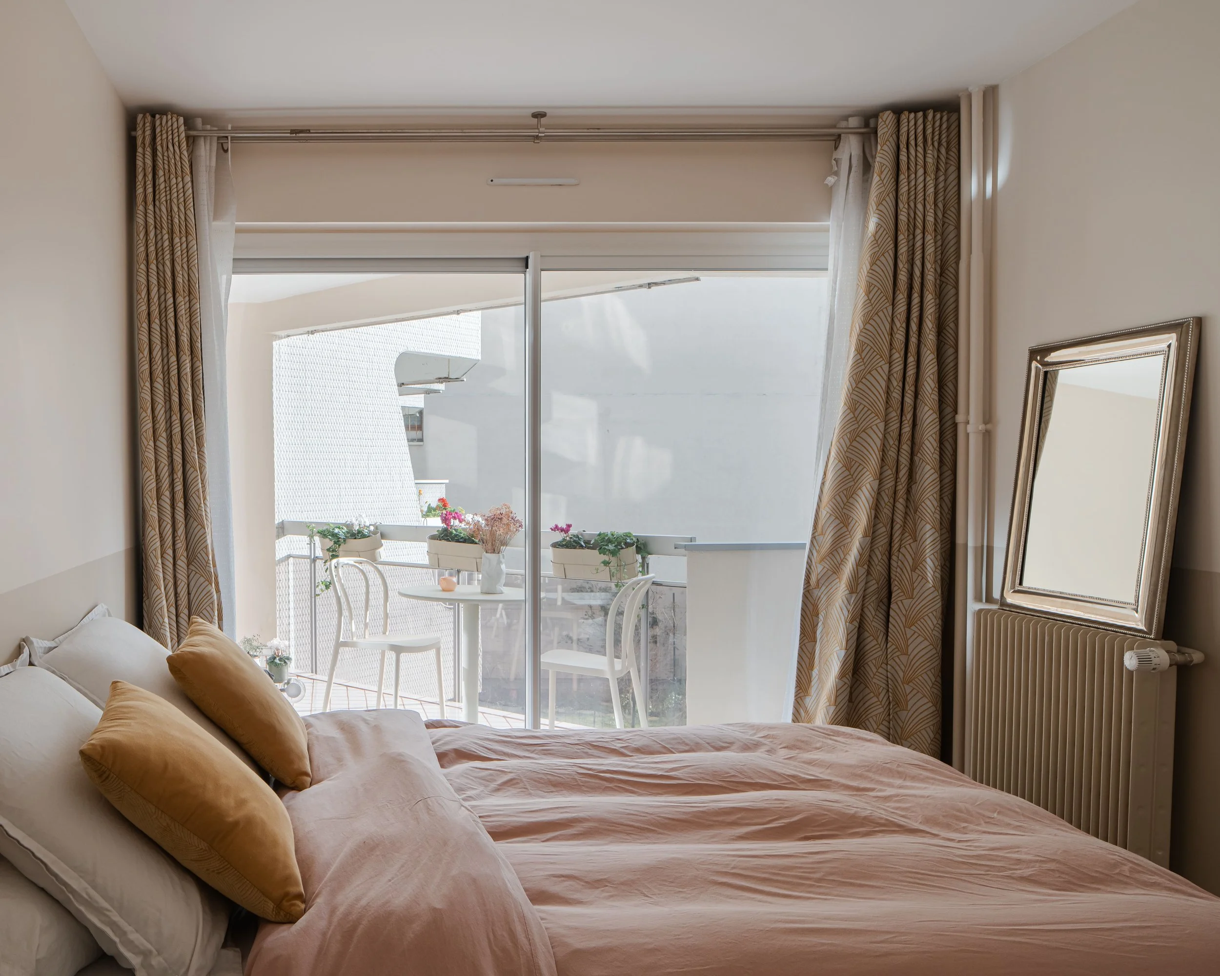 Chambre avec lit, oreillers et vue sur balcon avec table, chaises et plantes