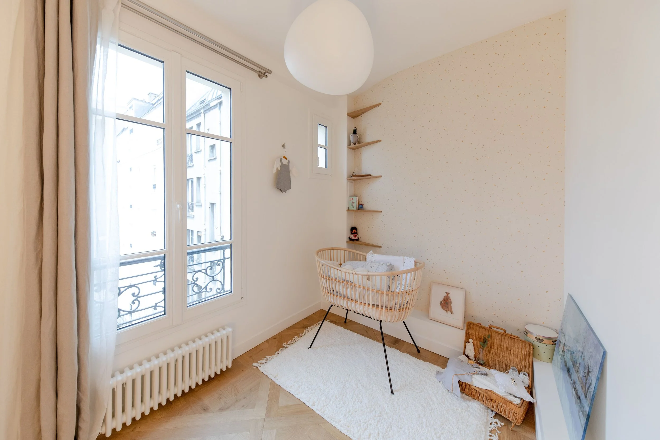 Table à langer pour bébé dans une chambre lumineuse avec une fenêtre, un tapis blanc, des étagères en bois et des décorations mignonnes.