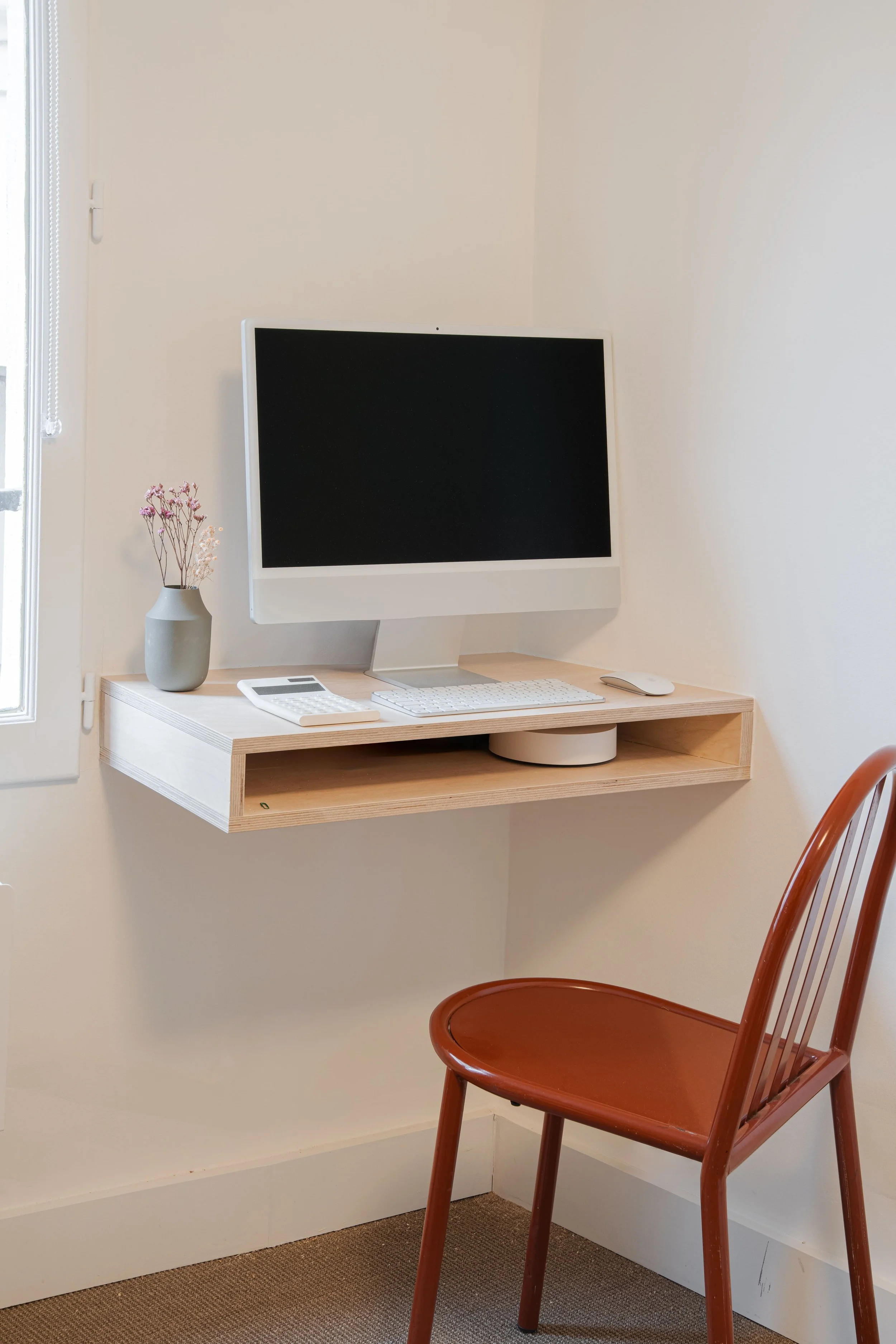 Bureau avec un ordinateur, une calculatrice, une souris, une plante, une fenêtre, et une chaise en bois.