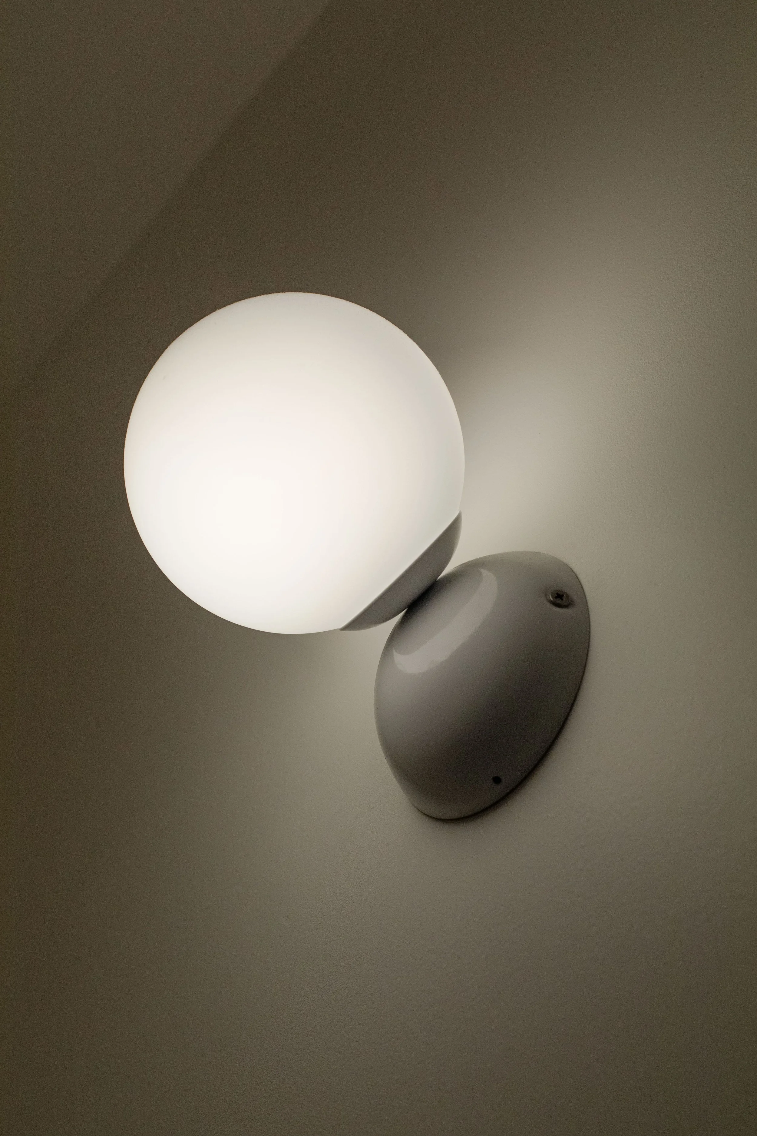 Applique murale avec une boule de lumière blanche sur un mur gris
