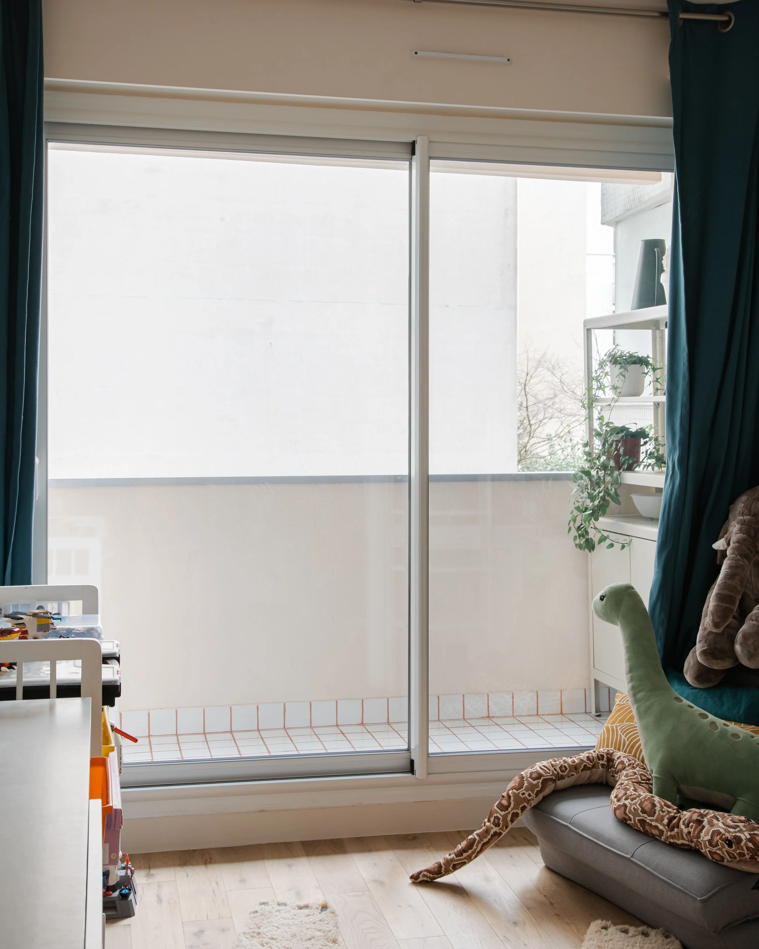 Balcon avec porte coulissante, jouets d'enfants, peluche, et décoration intérieure