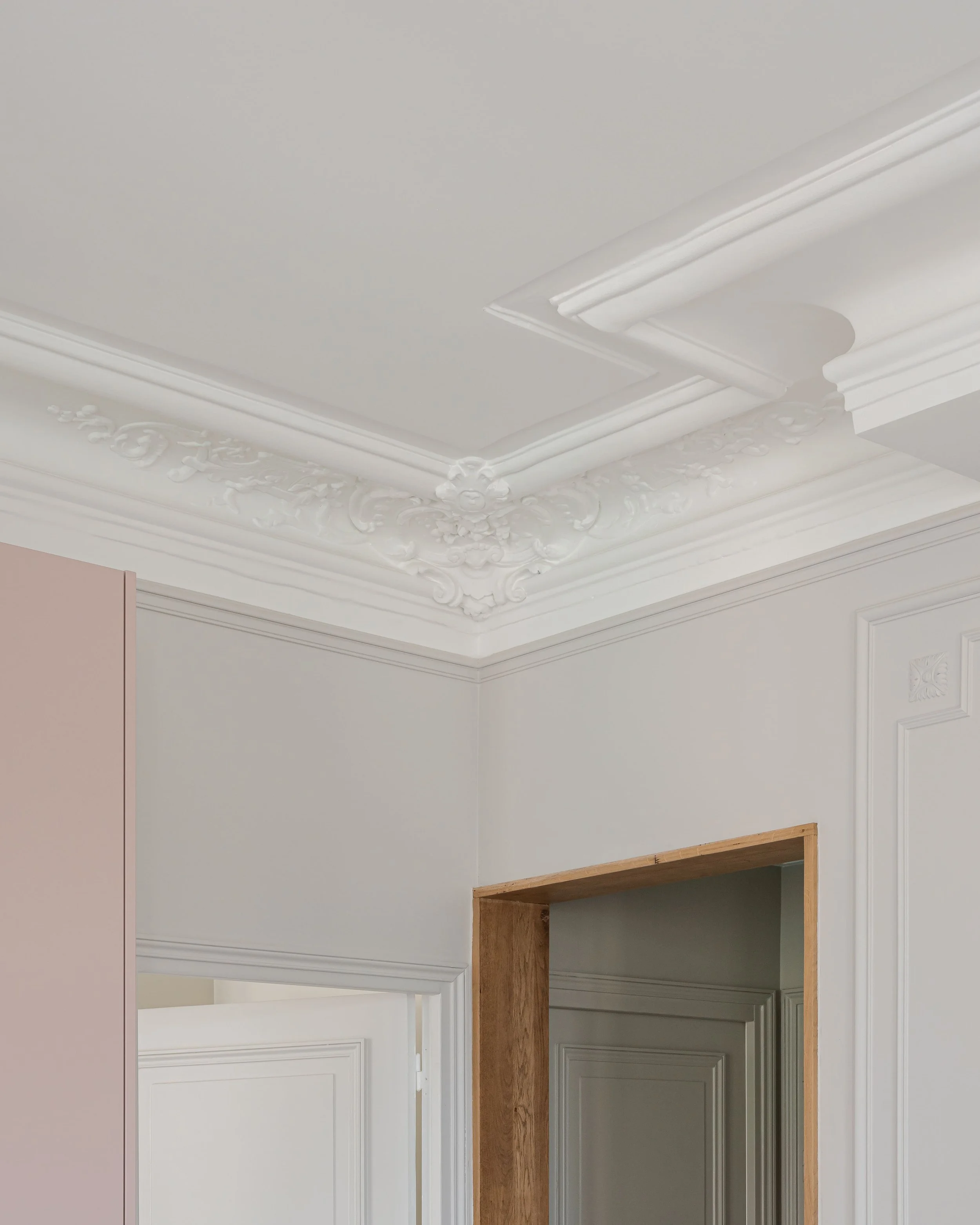 Détails d'un plafond orné de moulures et de décoration en plâtreories dans une pièce lumineuse.