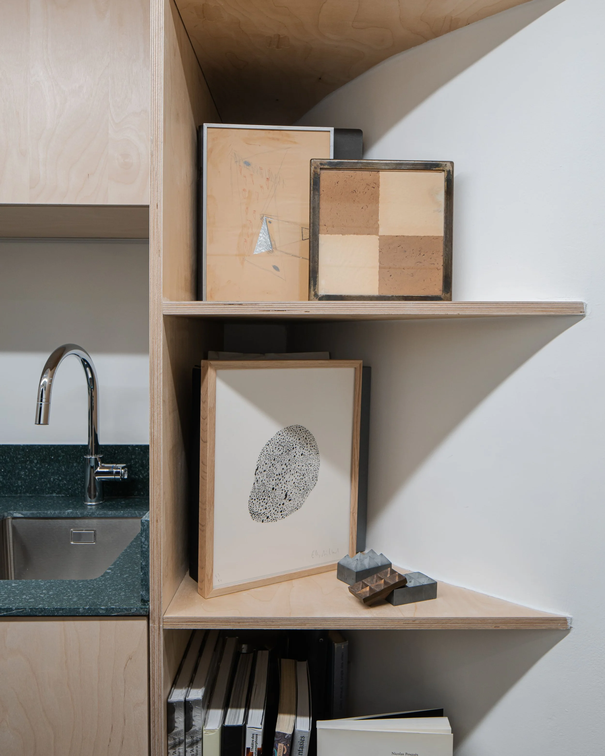 Étagère en bois avec des œuvres d'art modernes, des livres et des petits objets décoratifs dans une pièce moderne.