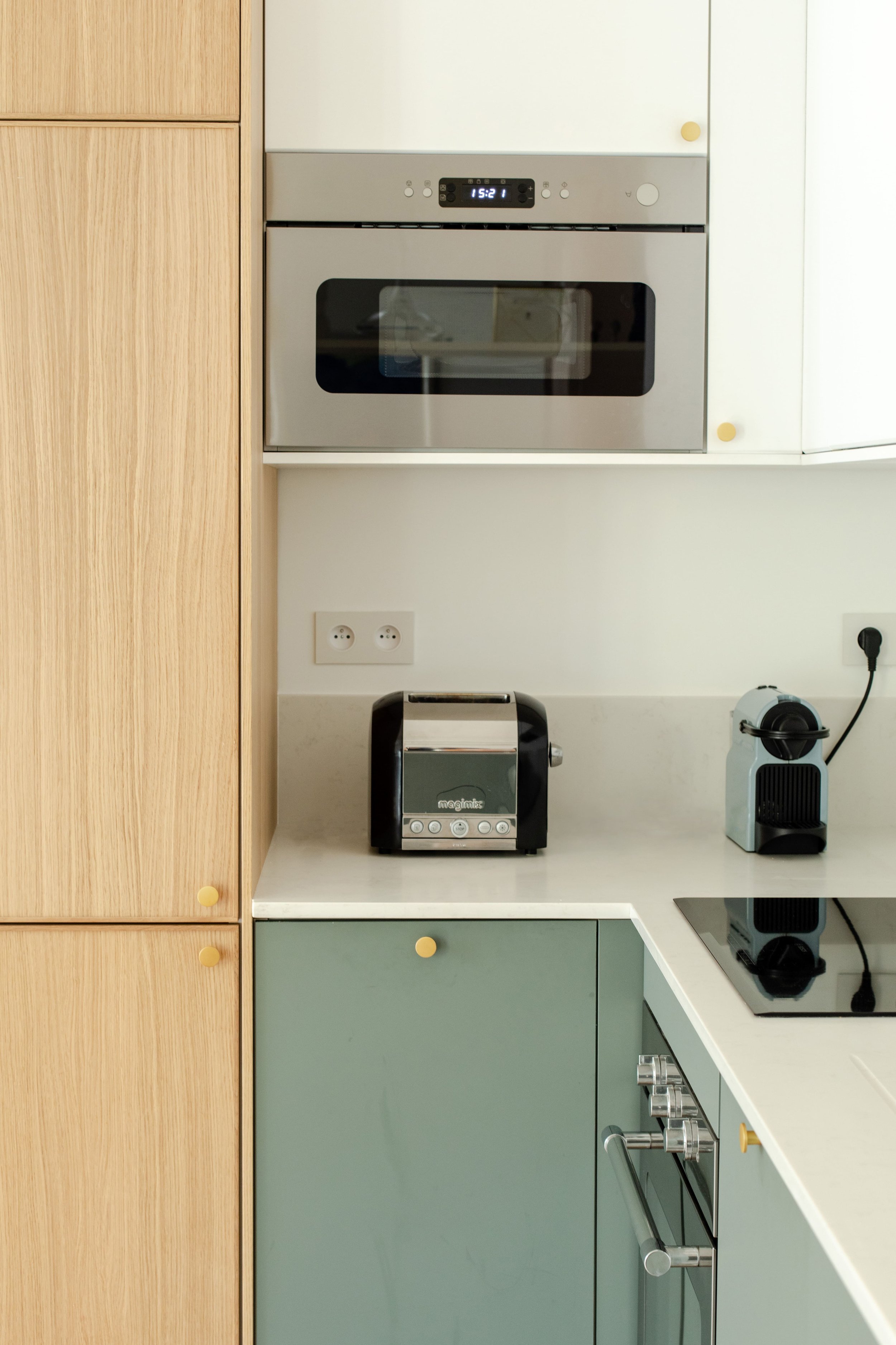 Cuisine moderne avec un four encastré, un grille-pain, une machine à café et une plaque de cuisson.