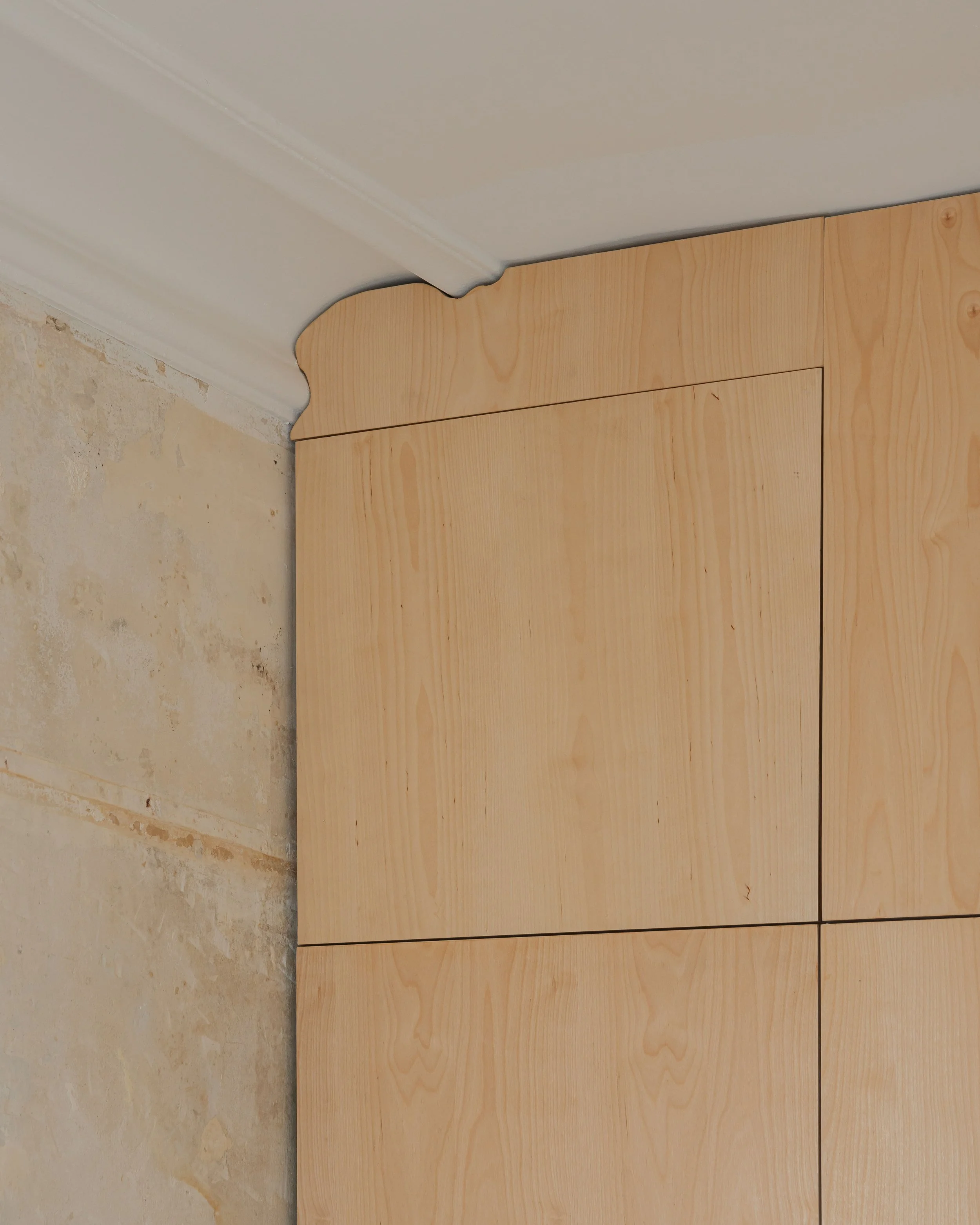 Les carreaux de bois clair sont installés près du plafond dans une pièce, avec un coin où il y a une moulure en forme de nuage.