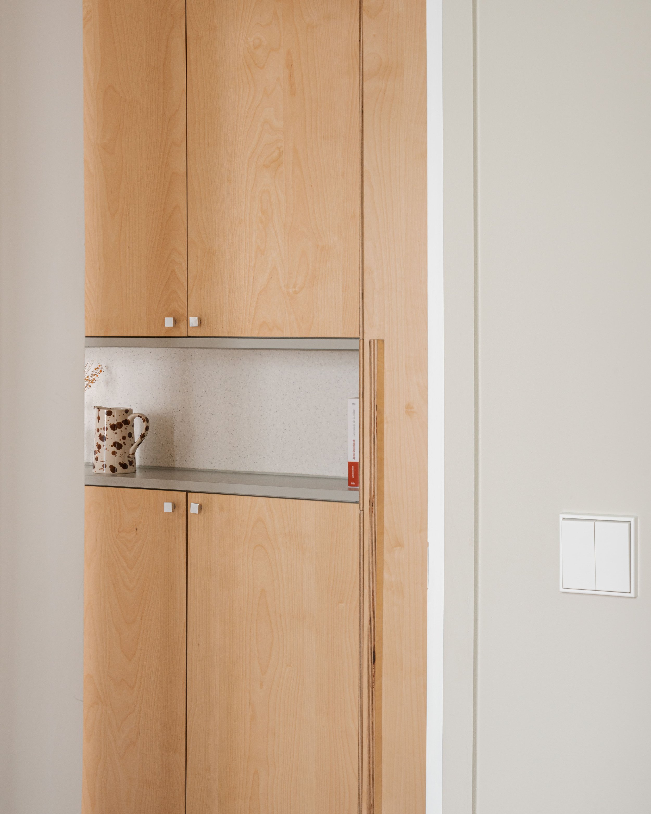 Armoires en bois clair dans une cuisine, avec un mug à pois sur une étagère