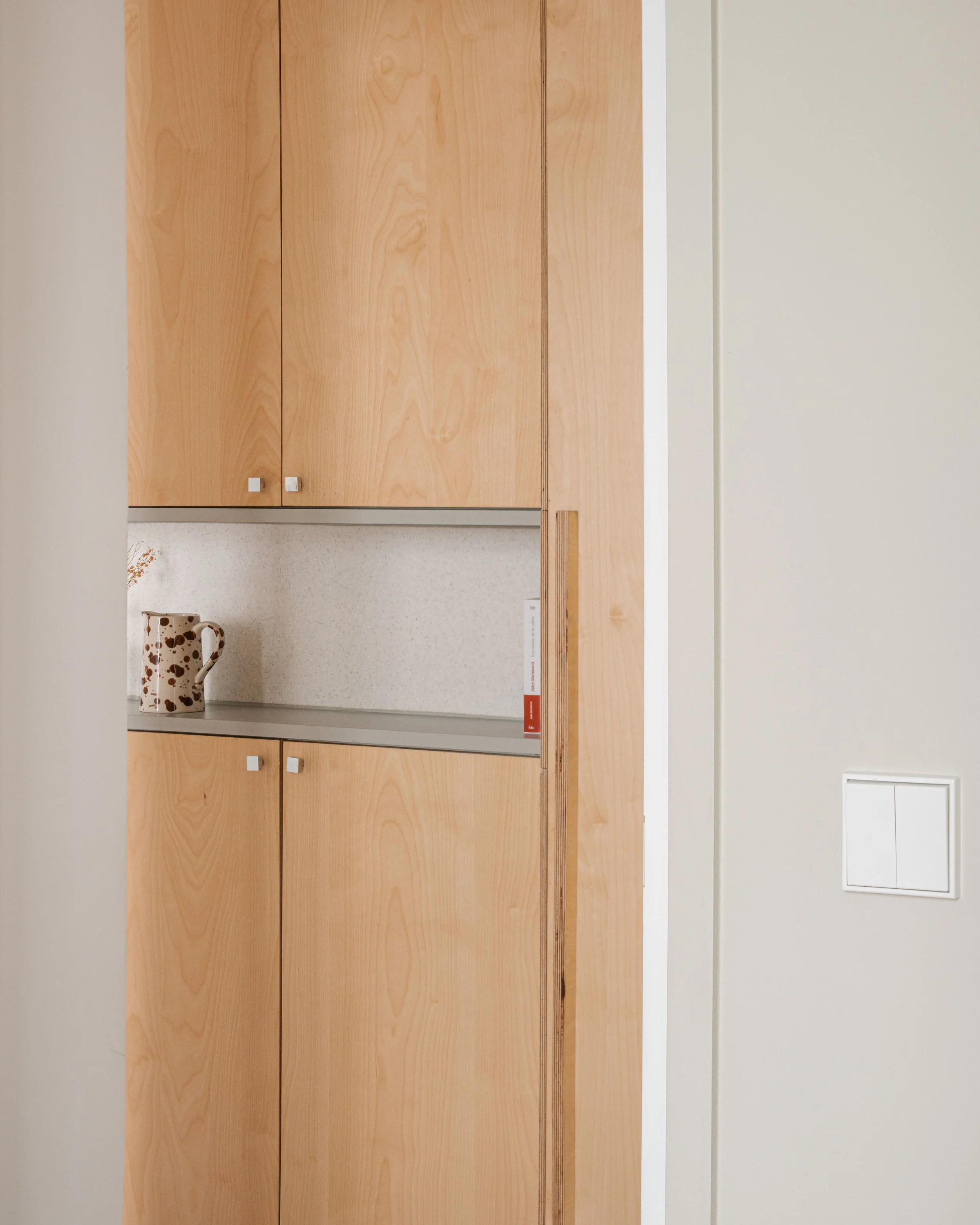 Une porte en bois orange clair avec une étagère contenant une cruche à pois