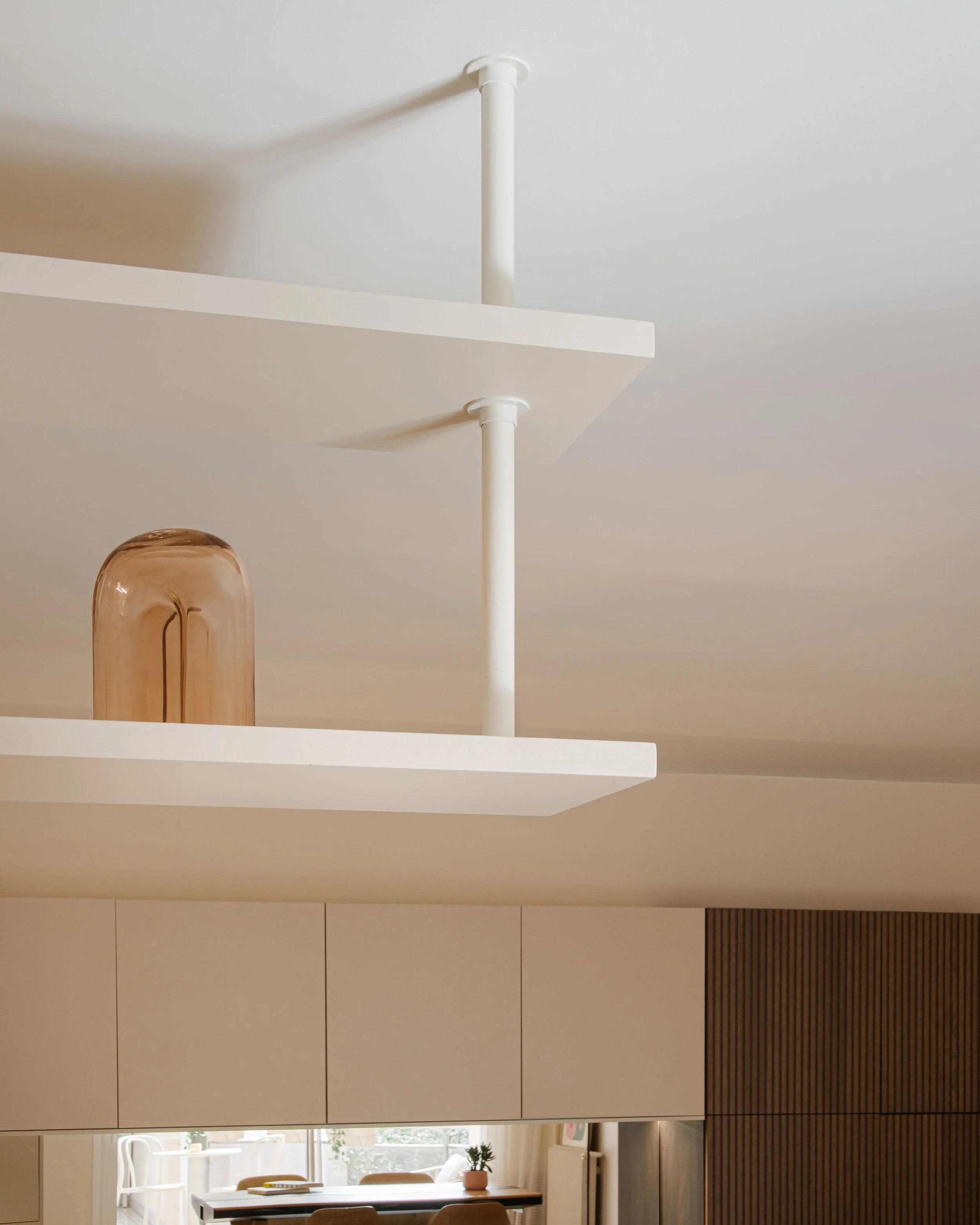 Une étagère blanche avec un vase en verre marron clair dans un intérieur moderne