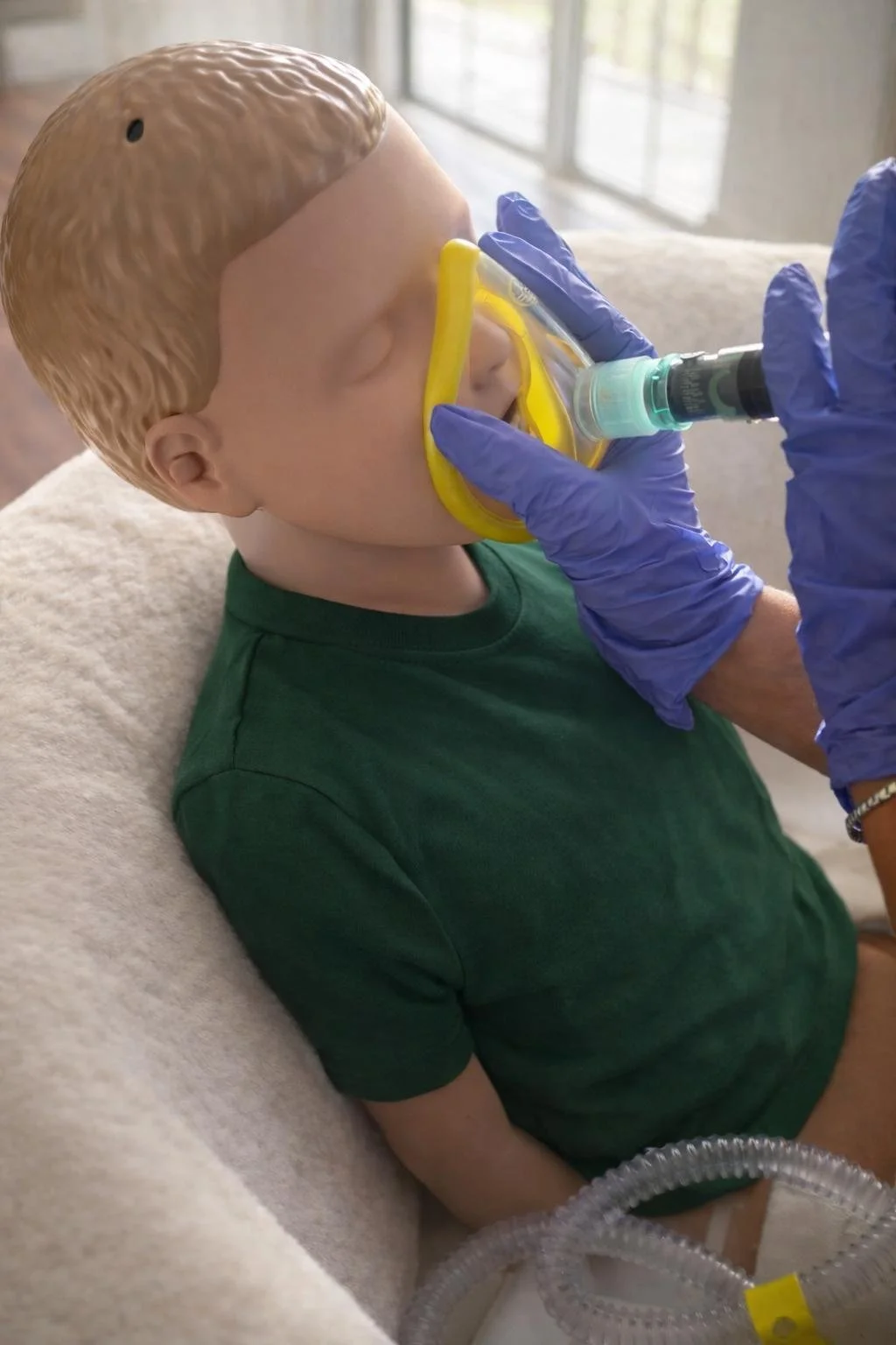 Learner delivering facial cough assist to child sim manikin