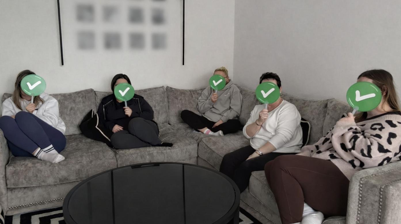 Team holding true or false paddles against faces in a client-centred home setting training session