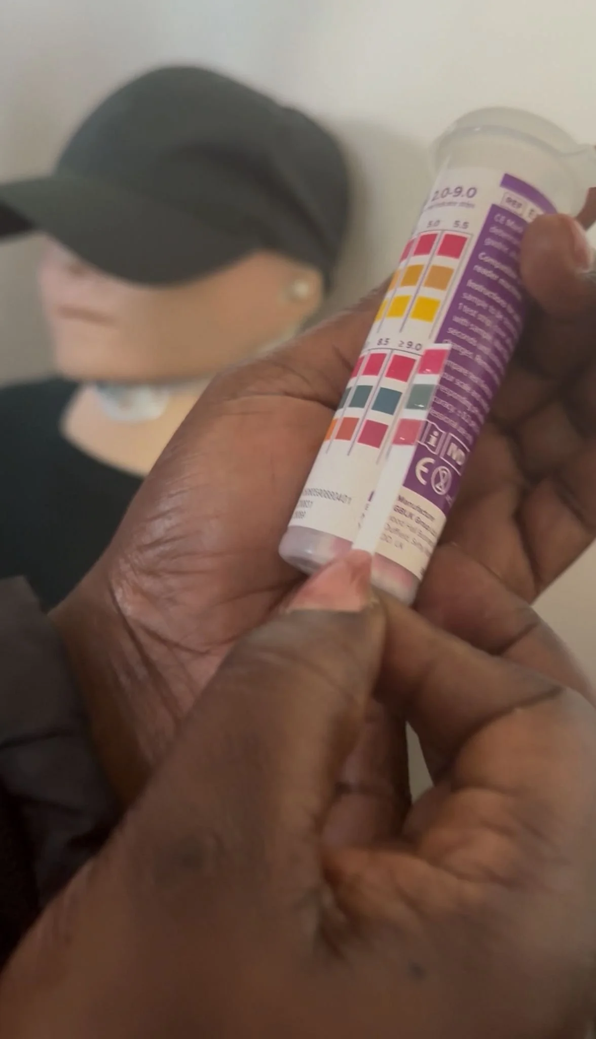 A person holding up a pH stick to the tub and seeing an alkaline reading