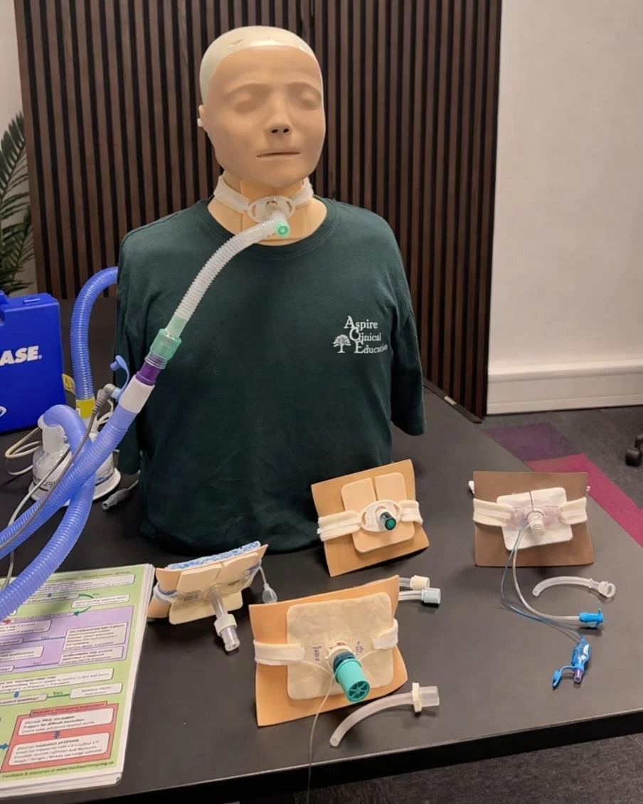 Sim manikin with various tracheostomy devices infront