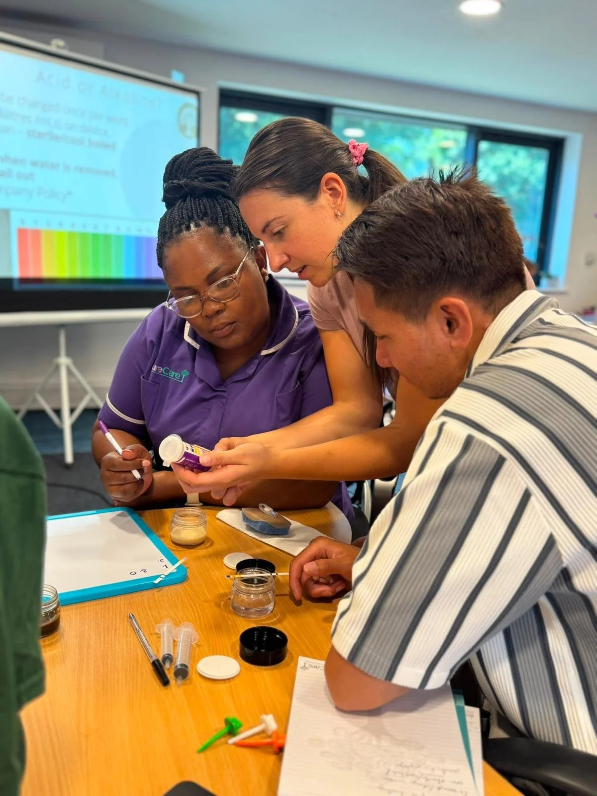 Heather demonstrating safe pH testing for PEG device confirmation with 2 learners