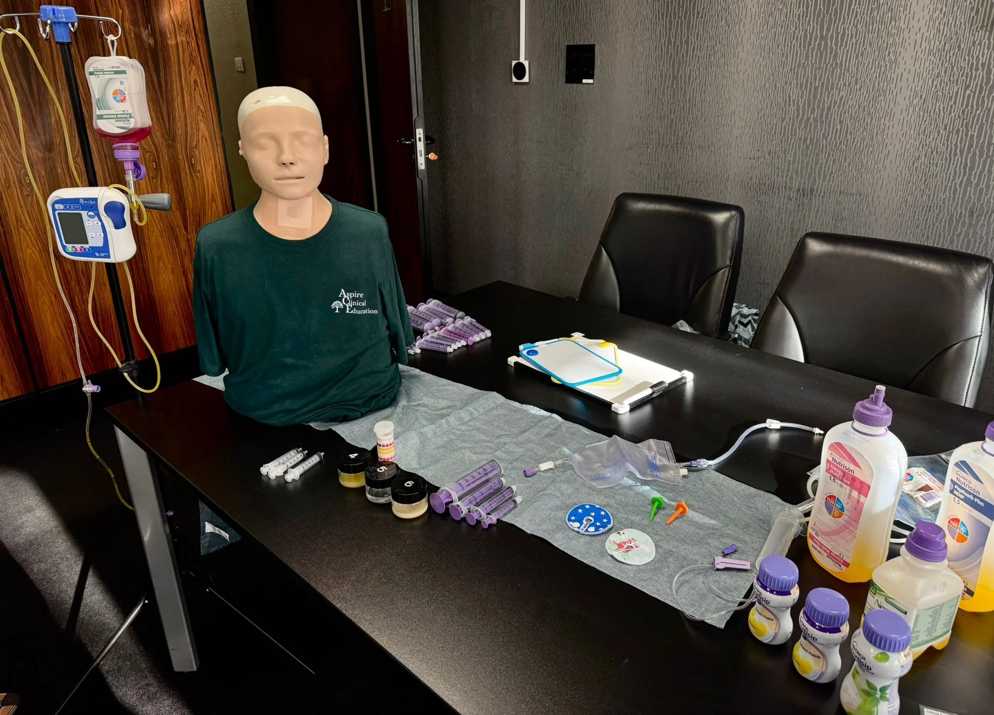 A table layout of various PEG feeding devices and products with a sim manikin and a feeding pump