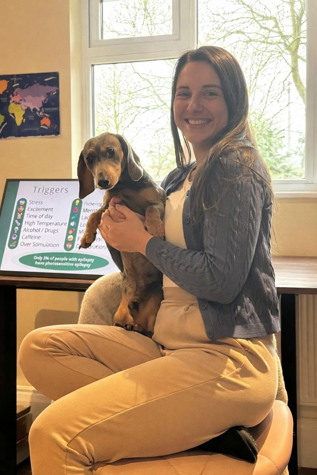 Heather holding a small dog whilst delivering client-centred epilepsy training at a client home