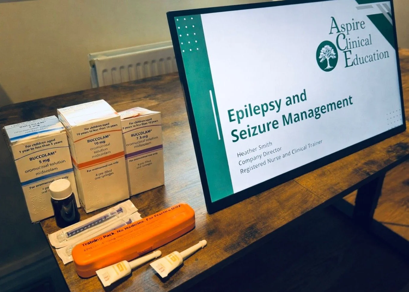 Training monitor displaying epilepsy training with training rescue medications next to it, buccolam and epistatus, rectal diazepam