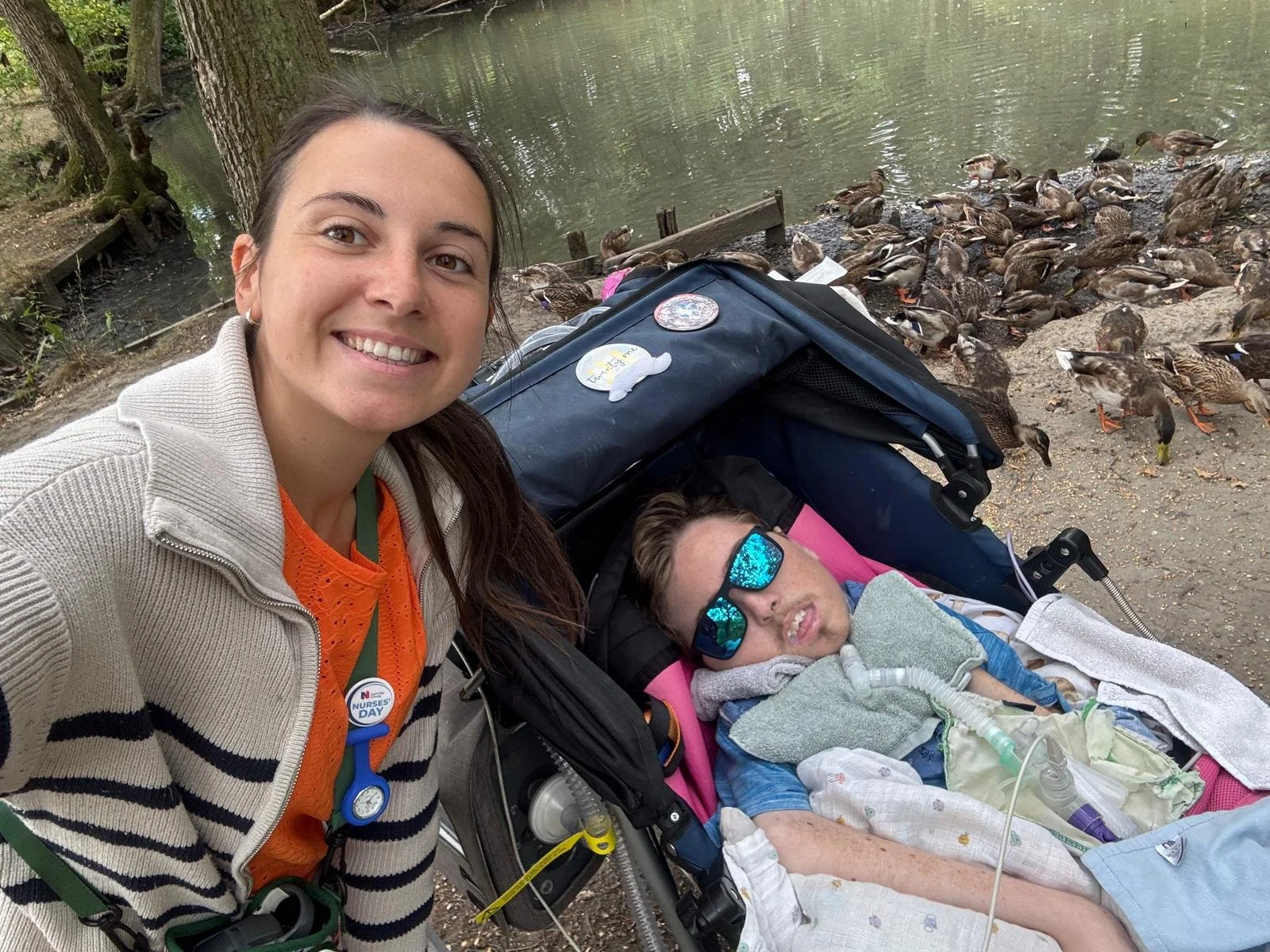 Heather with her nursing client at the pond with some ducks behind client wheelchair