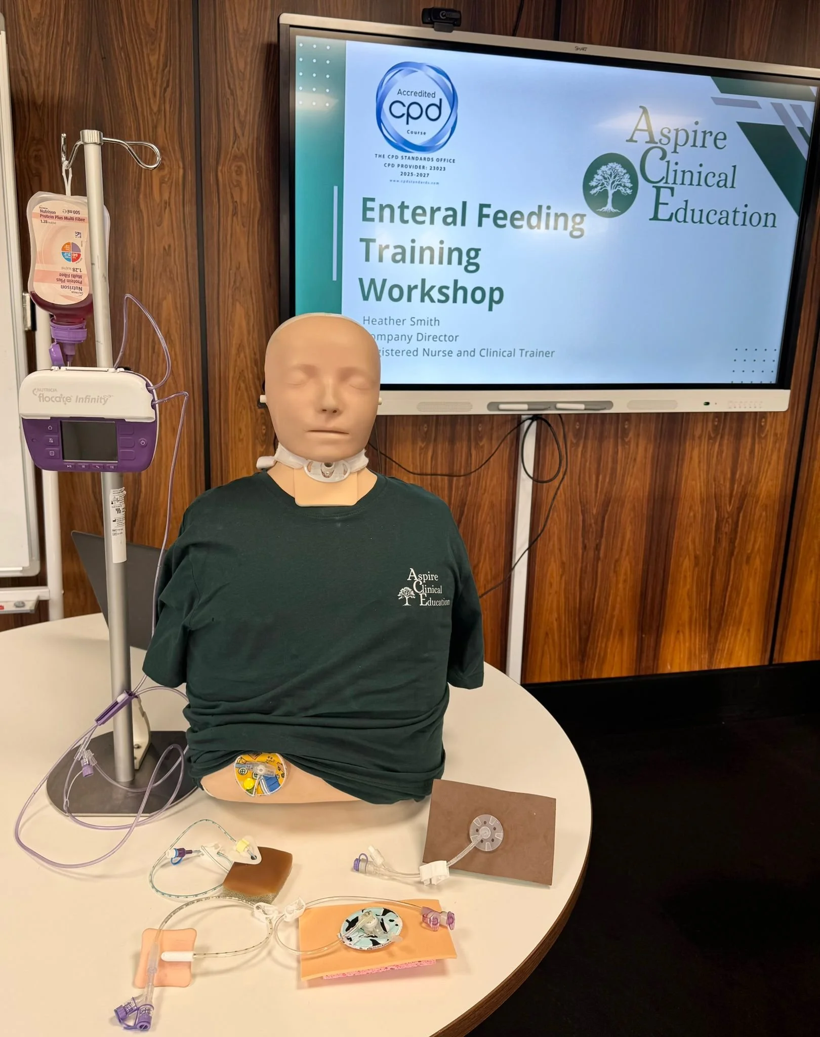 Sim manikin with PEG devices against presentation for enteral feeding training workshop
