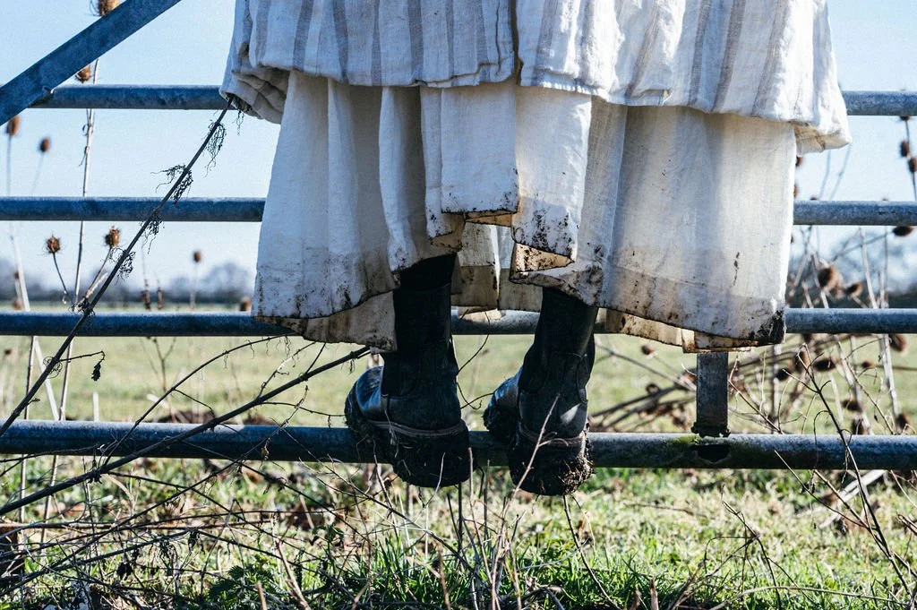 Muddy hems on linen clothes and walking boots.