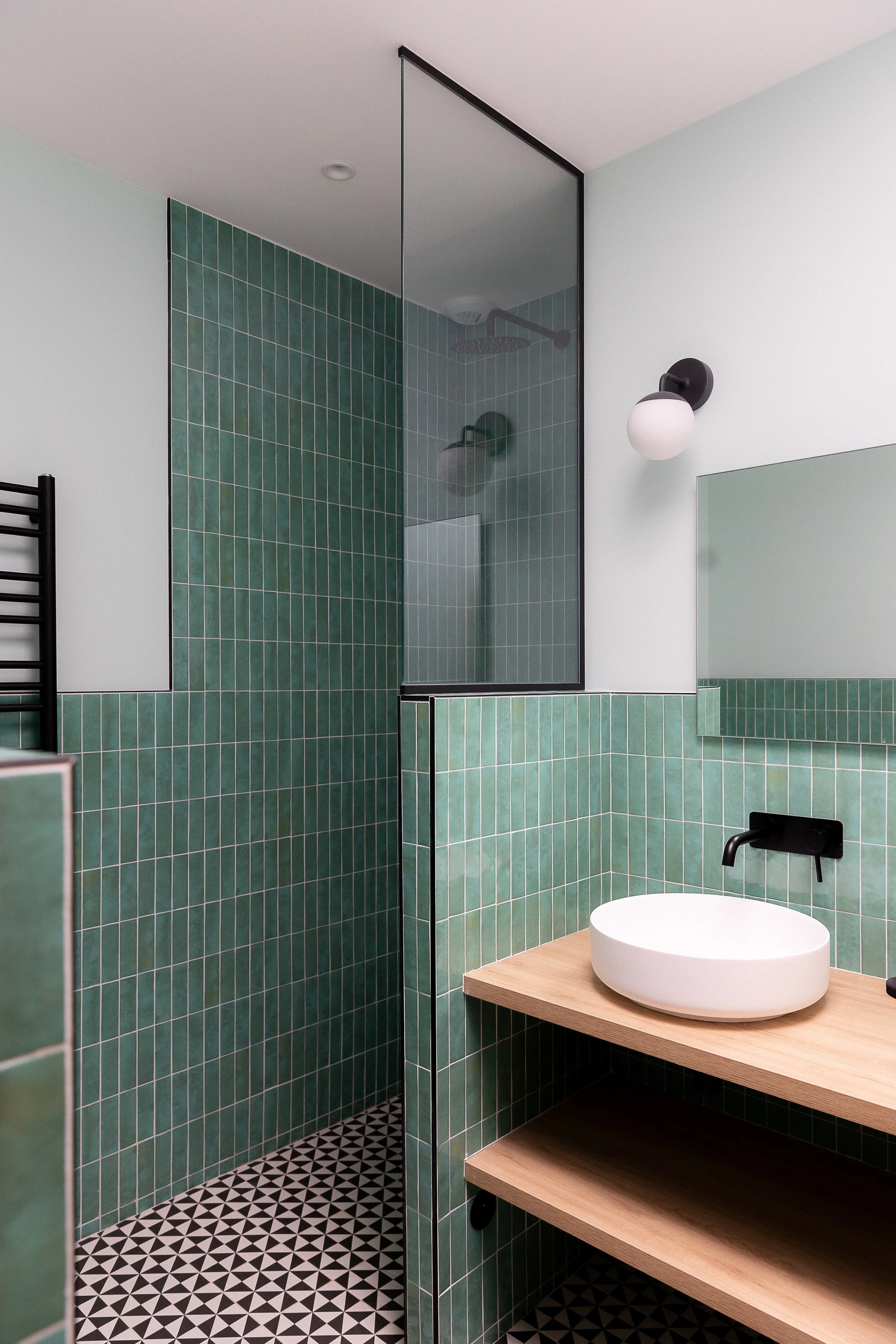 Salle de bain rénovée avec faience verte et sol en carrelage Noir et Blanc