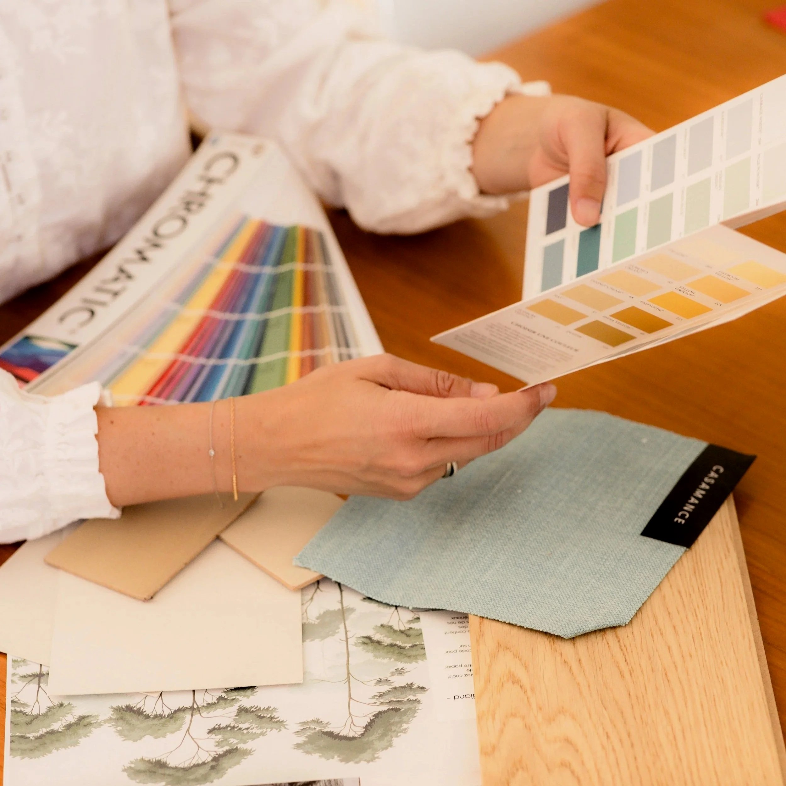 Échantillons de couleurs et de textures de matériaux et de papiers posés sur une table en bois
