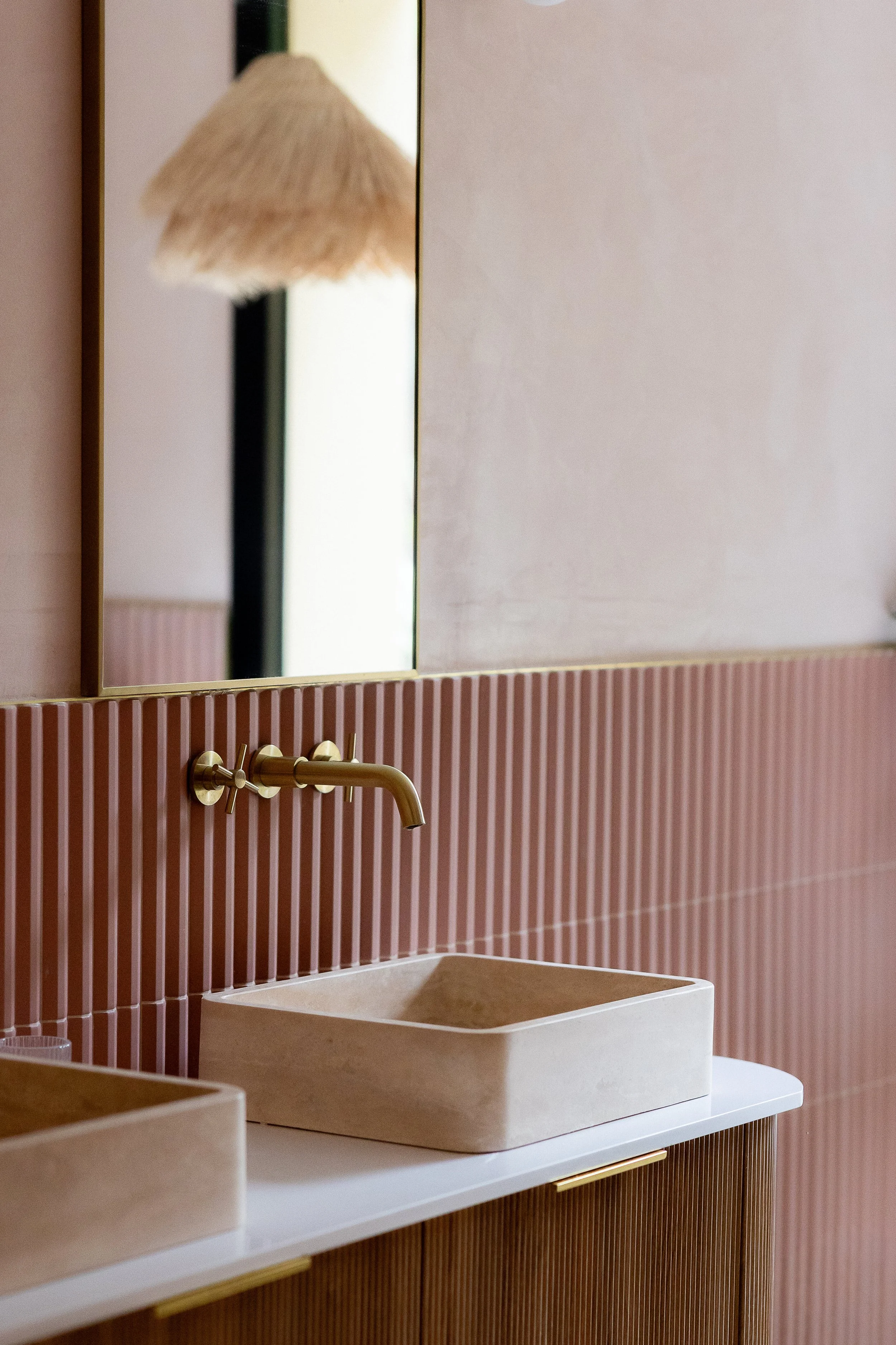 Salle de bain tout en douceur dans des teintes pastels de rose, associé avec du bois cannelé et du travertin