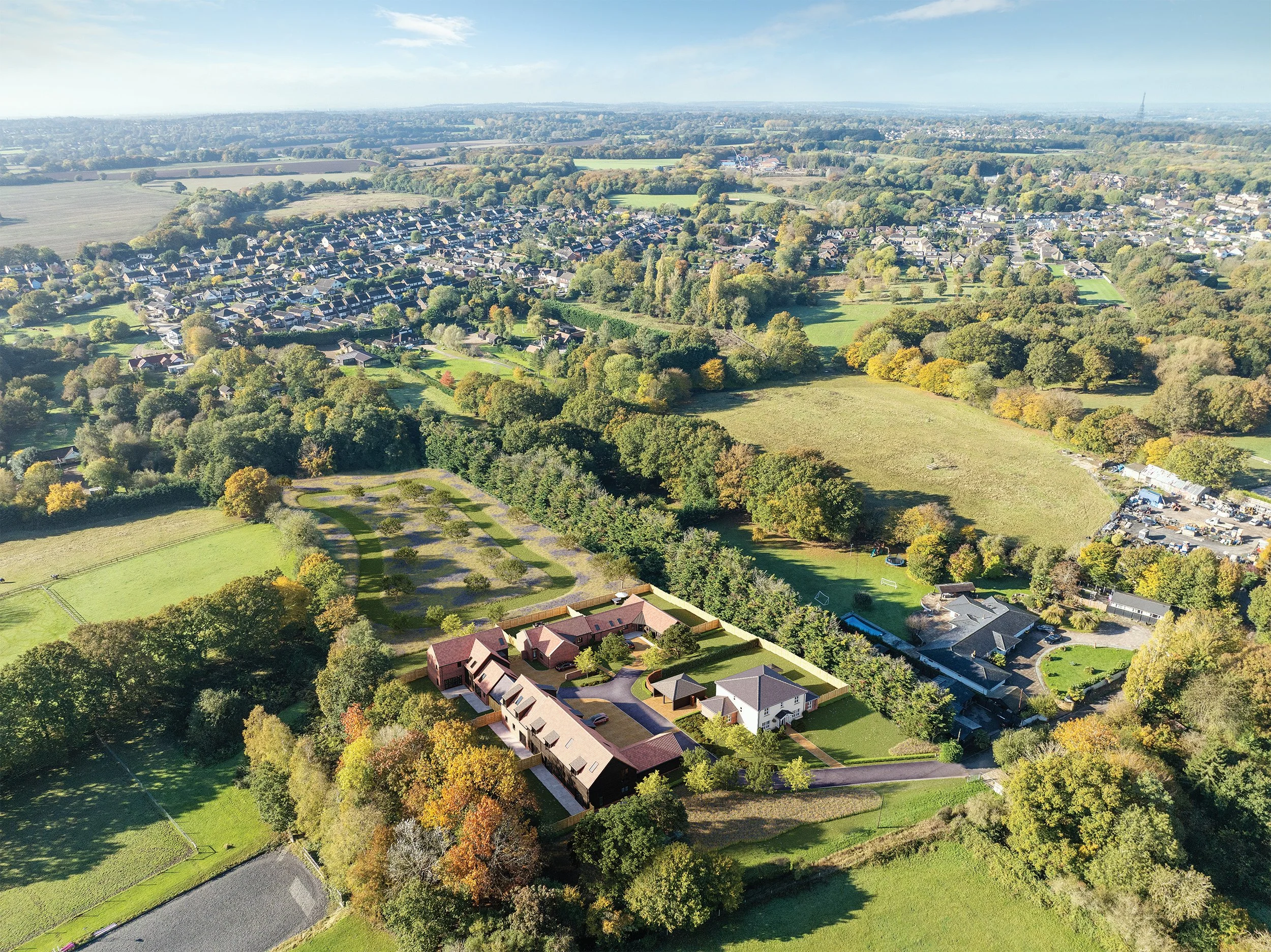 Aerial view of a suburban neighborhood with houses, trees, and open green spaces, taken on a clear day.